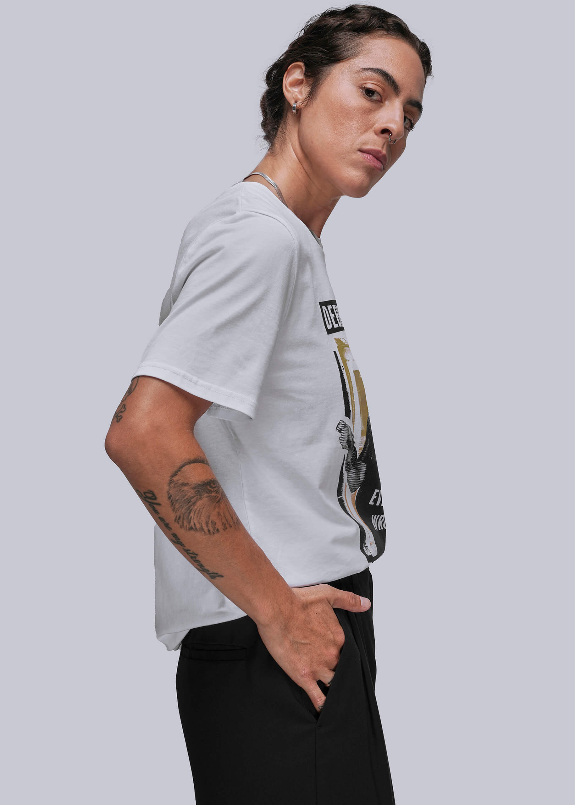 Person wearing a white t-shirt with a graphic design on a plain background