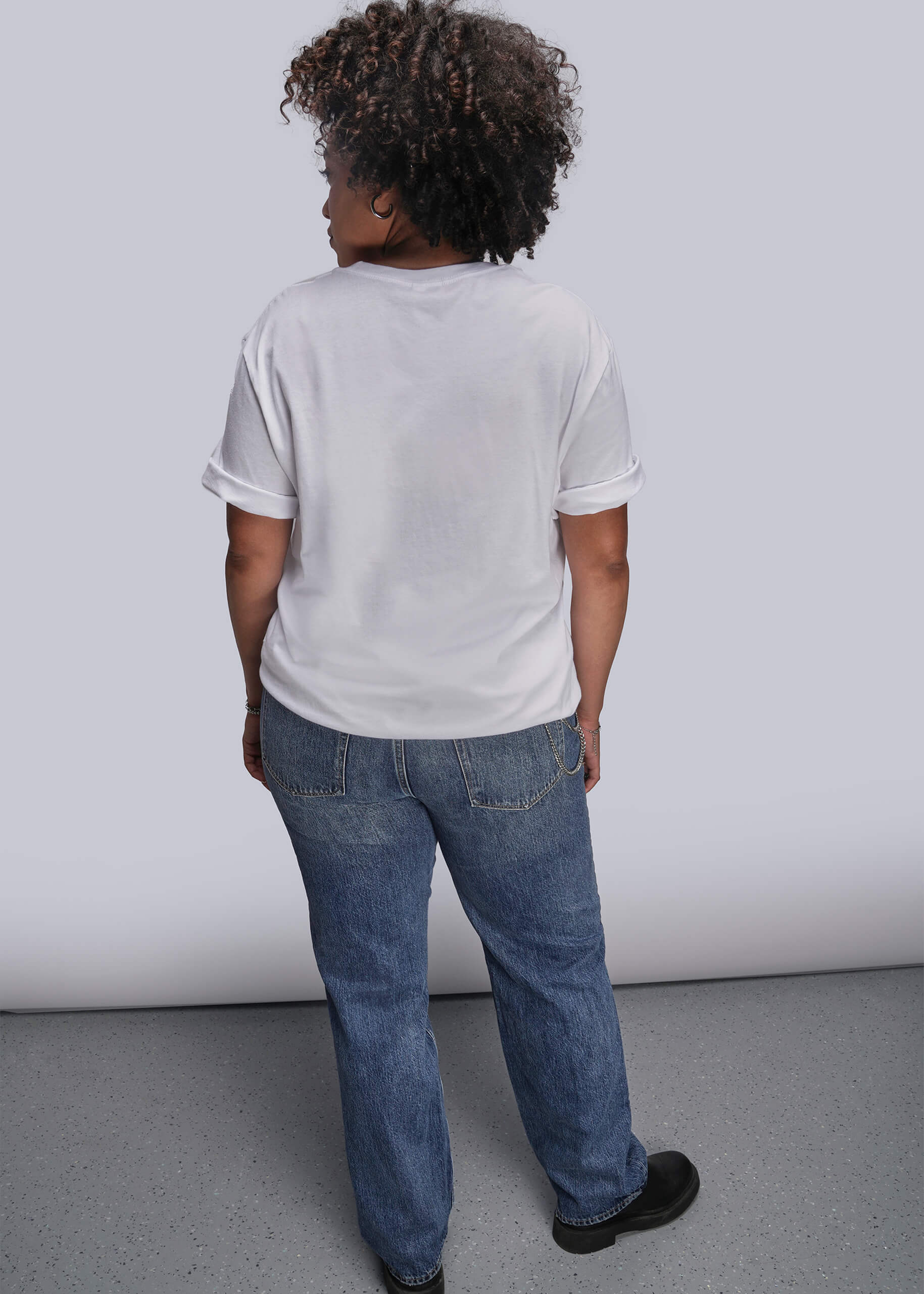 1X=Person wearing a white t-shirt and blue jeans standing against a plain background