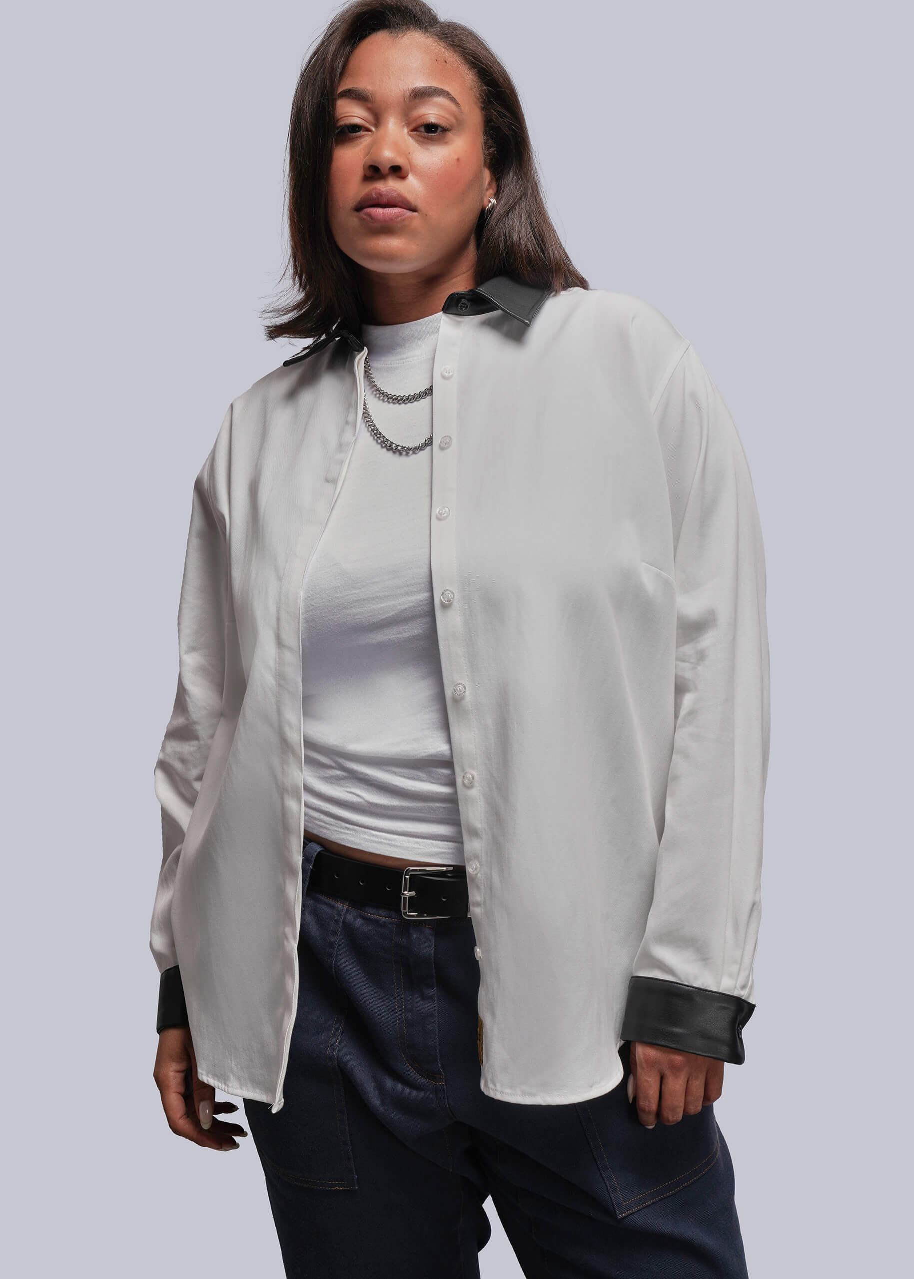 1X=Person wearing a white shirt with black cuffs and trim on a plain background
