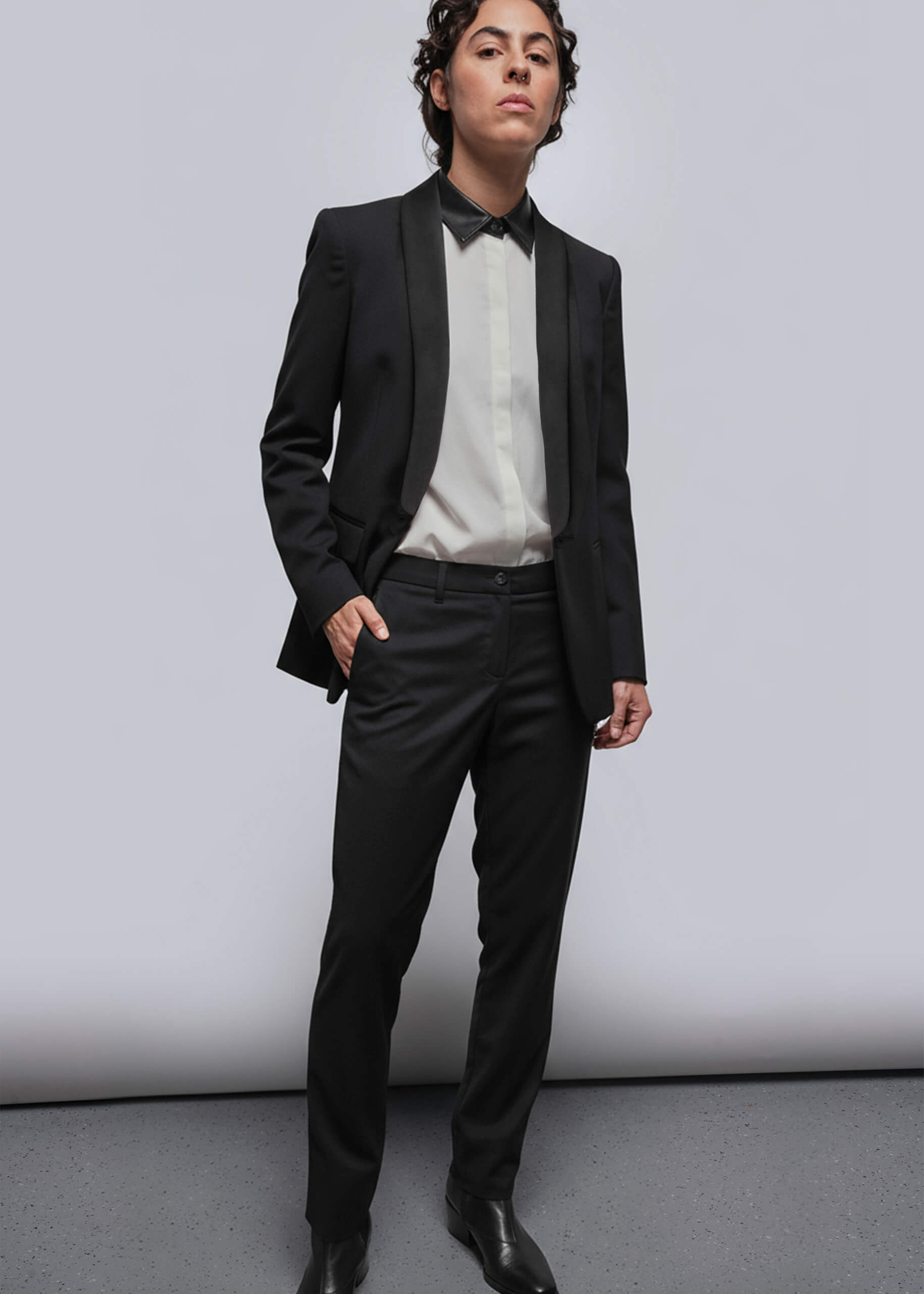 S=Person wearing black suit with white button up that has vegan leather collar