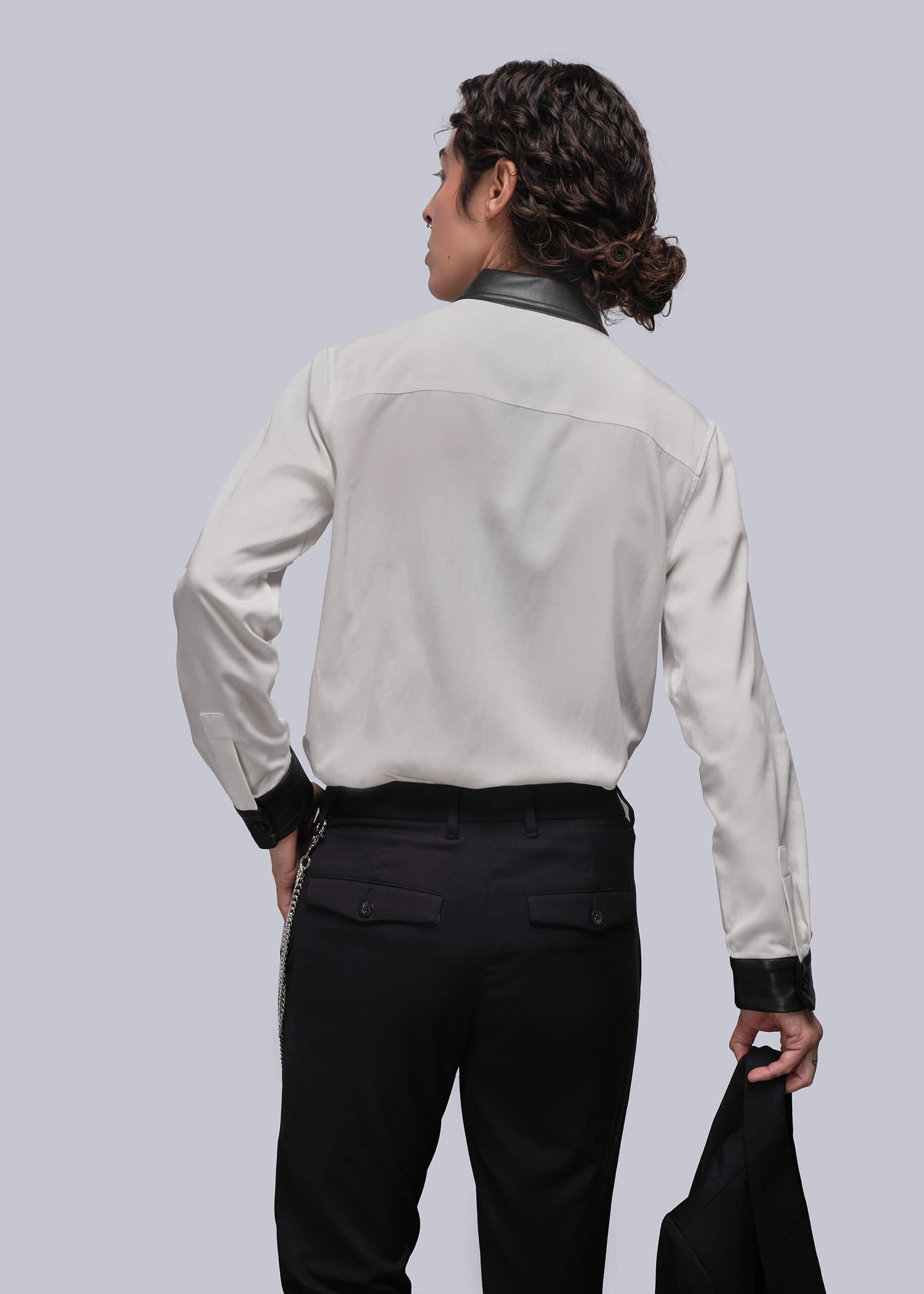 S=Person wearing a light-colored button up with black cuffs and trim on a plain background