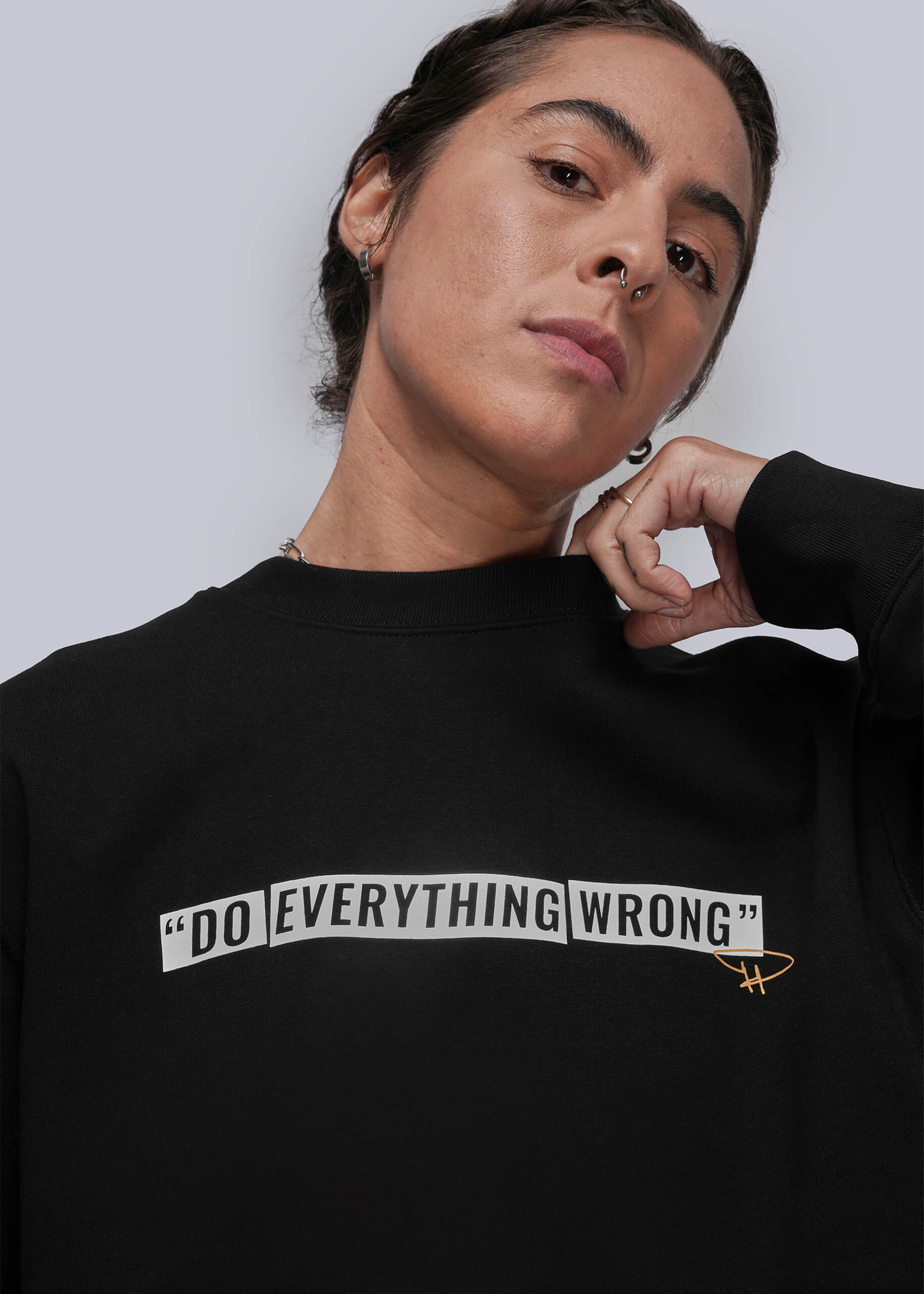 Person wearing a black sweatshirt with 'DO EVERYTHING WRONG' text on a plain background