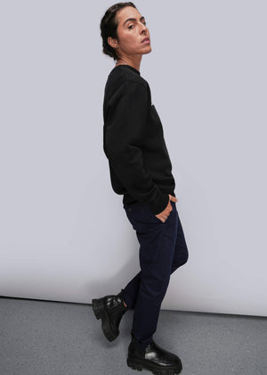 S=Person wearing a black sweatshirt and dark pants against a plain background