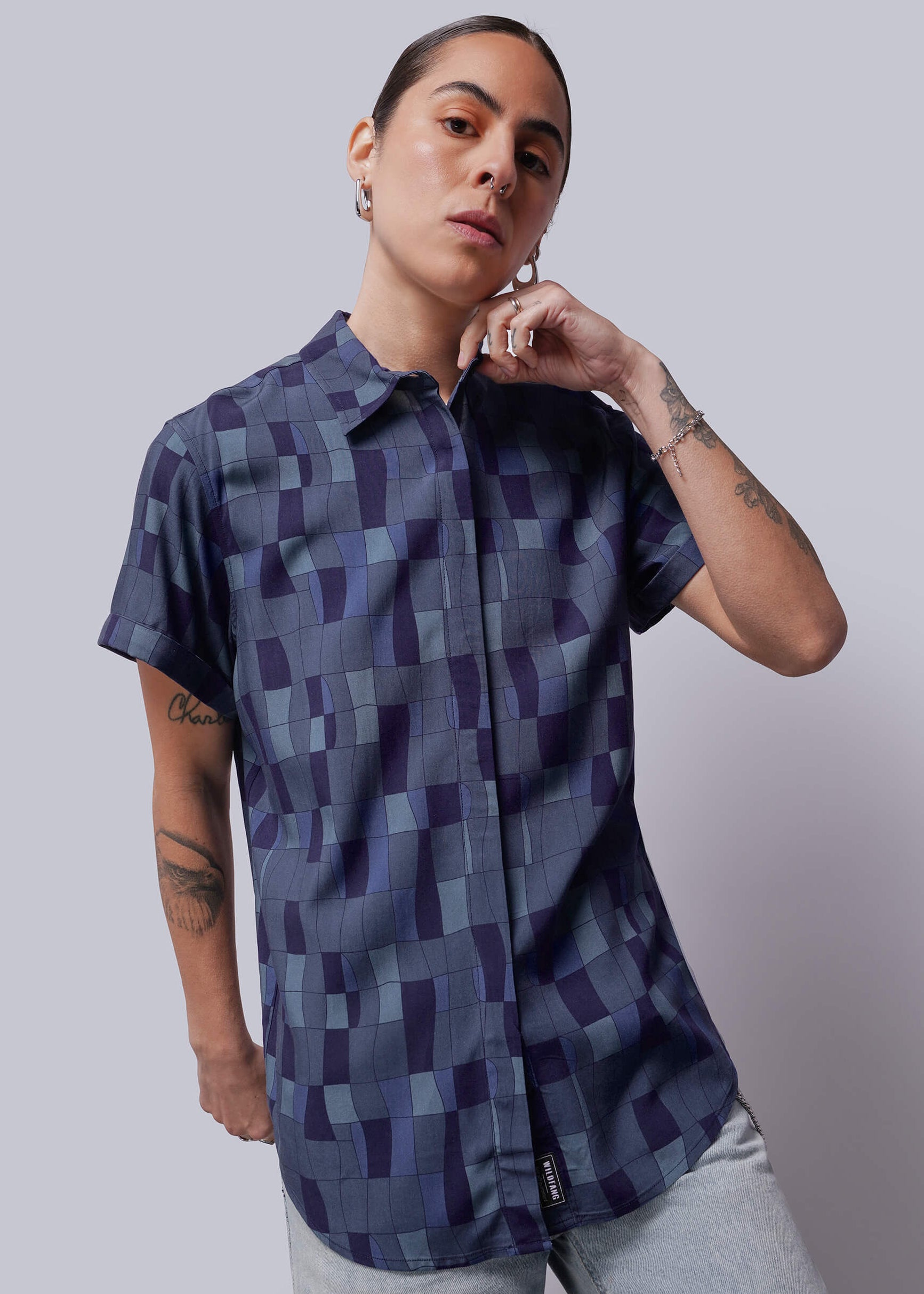 Person wearing a patterned shirt against a plain background