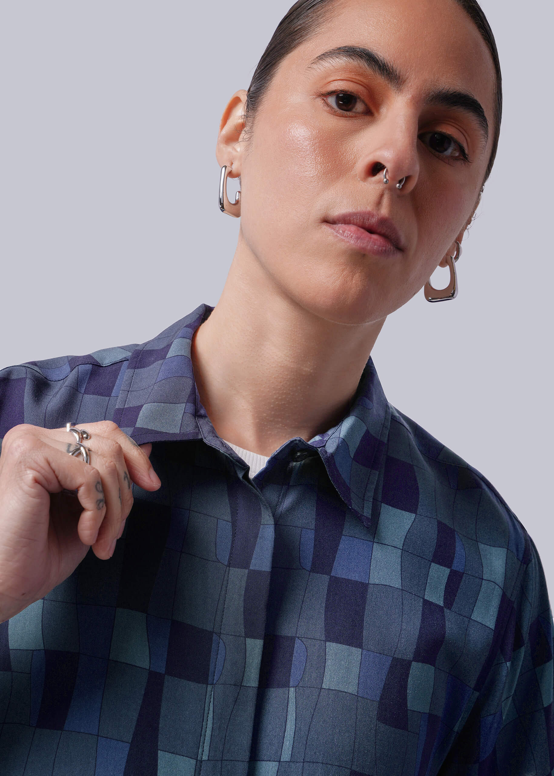 Close up of person wearing a blue patterned shirt against a plain background