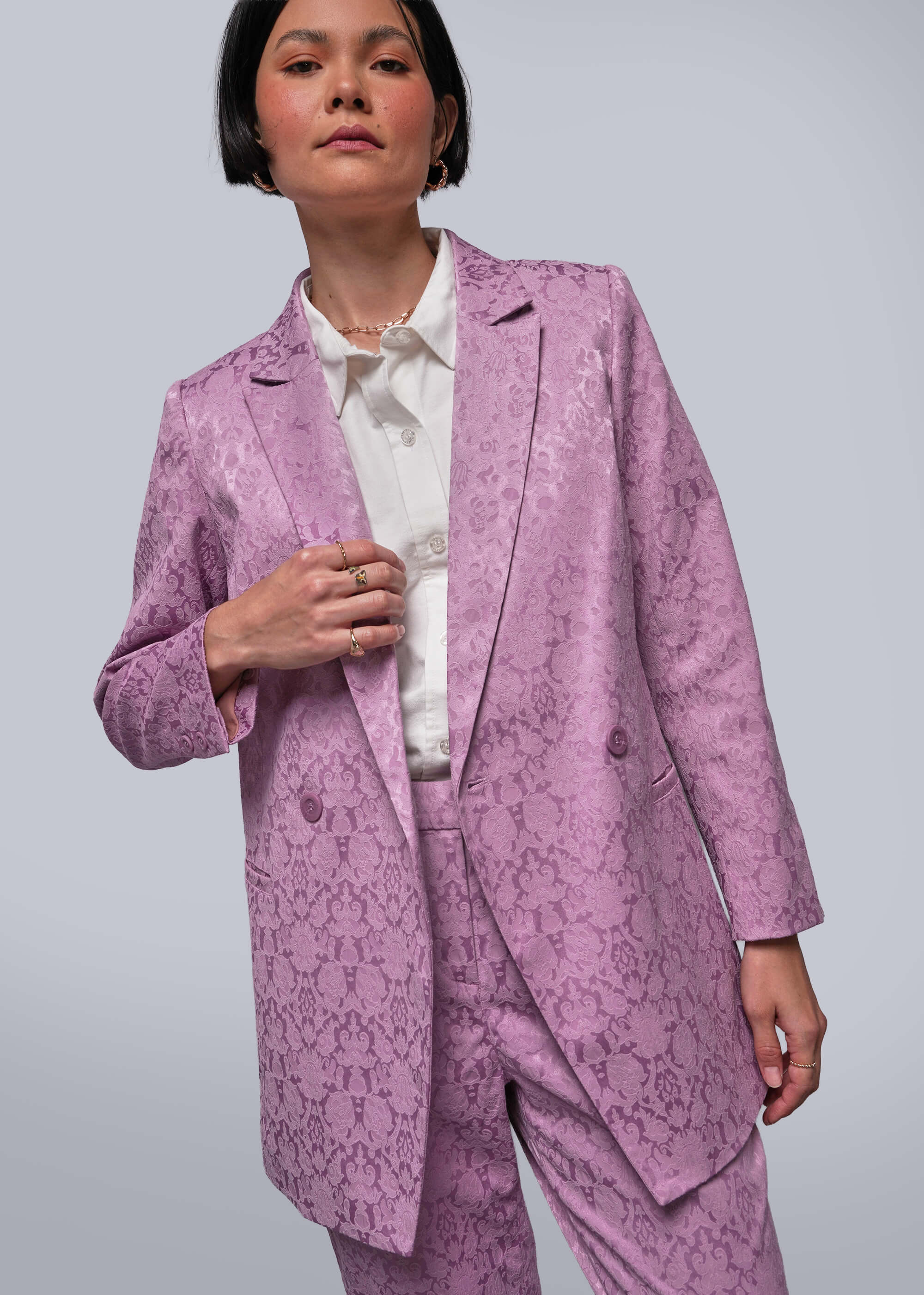 Person wearing a pink patterned suit against a plain background