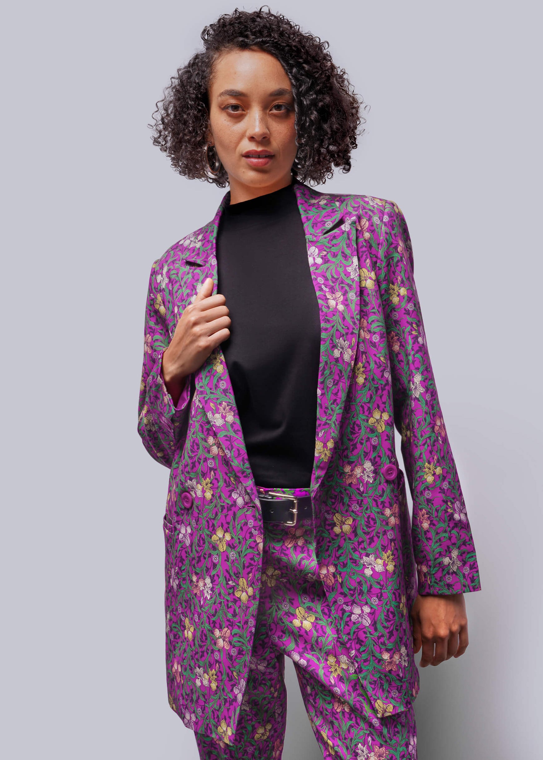 Woman wearing a purple floral suit against a gray background