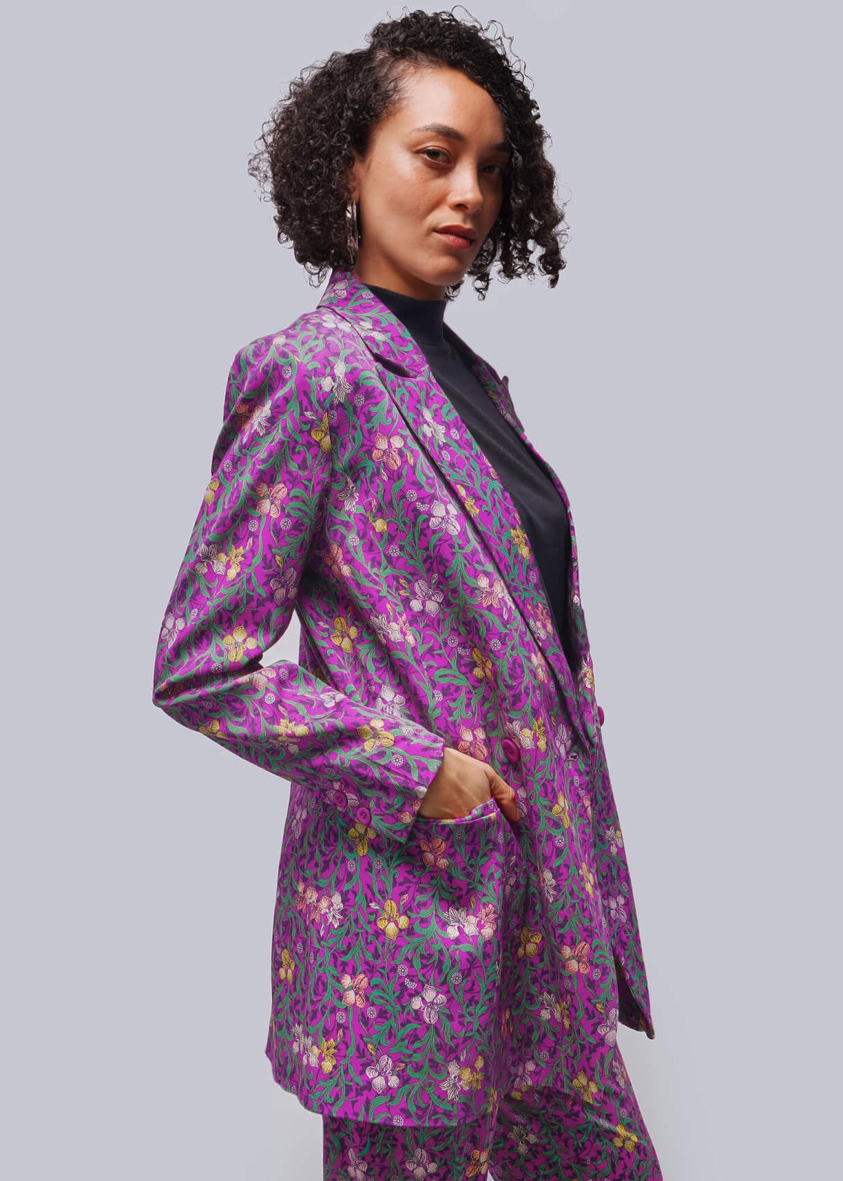 Person wearing a purple floral suit against a plain background