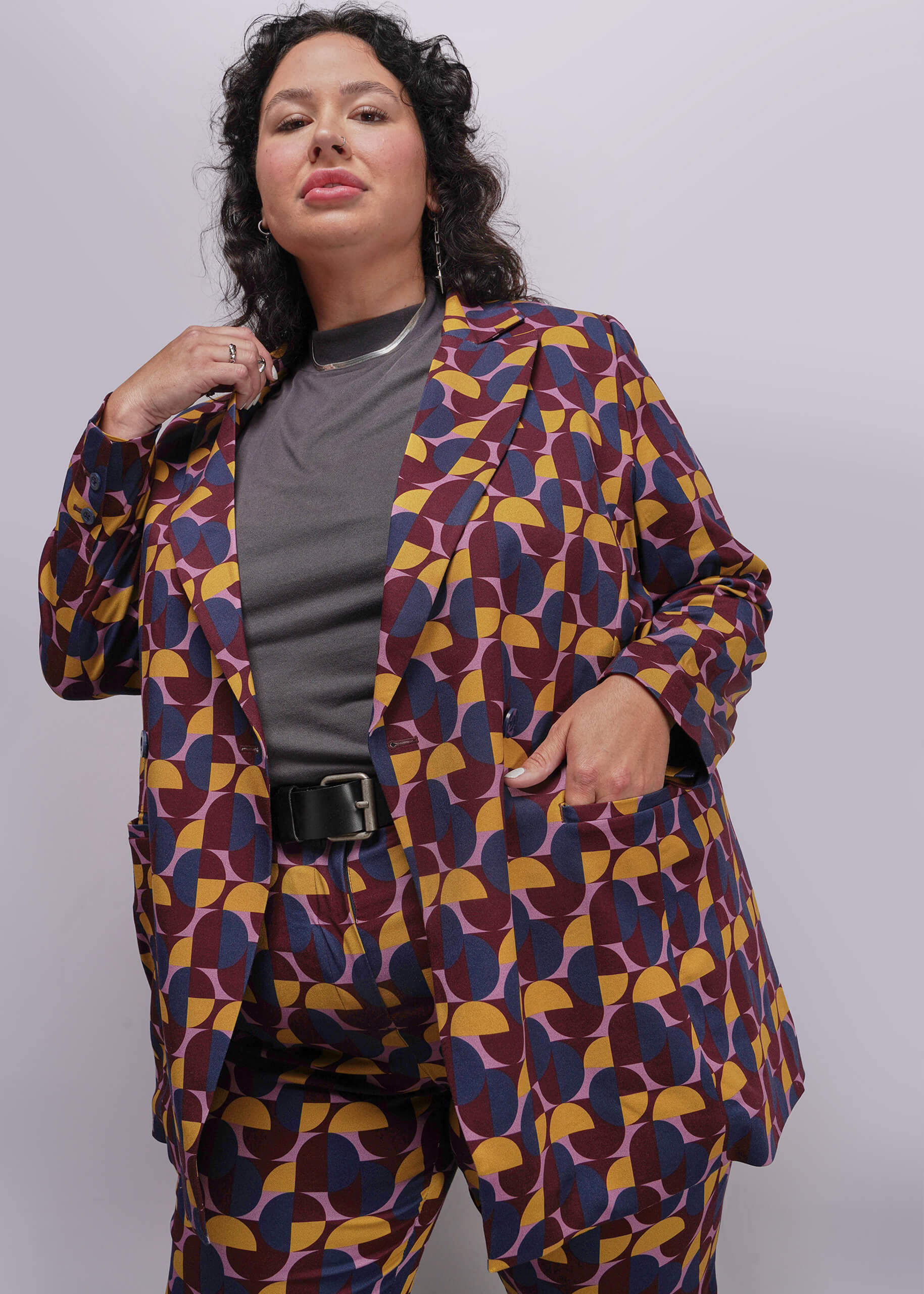 1X=Person wearing a colorful geometric-patterned suit against a plain background