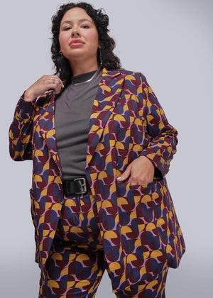 1X=Person wearing a colorful geometric-patterned suit against a plain background