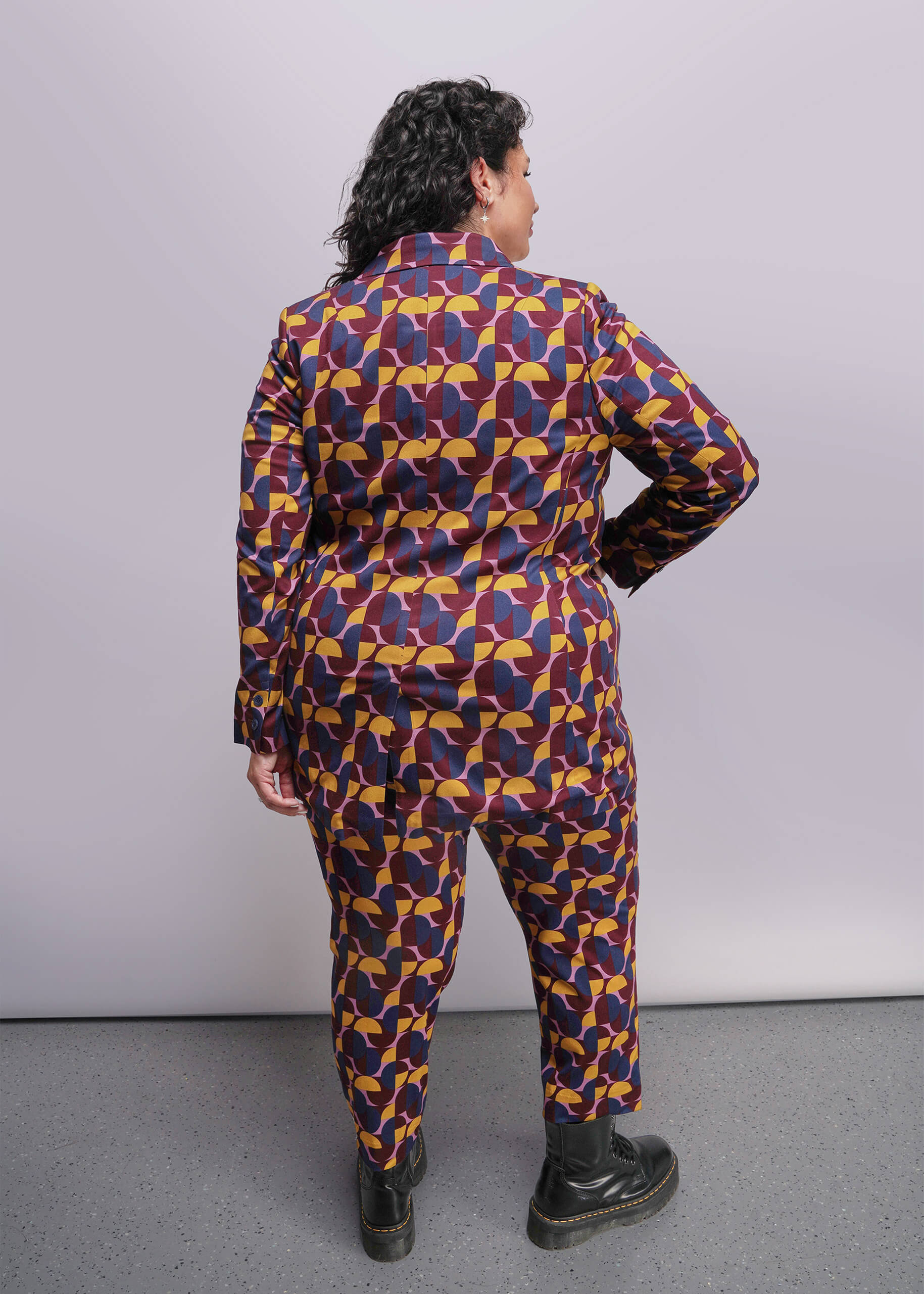 1X=Person wearing a colorful geometric patterned outfit against a plain background
