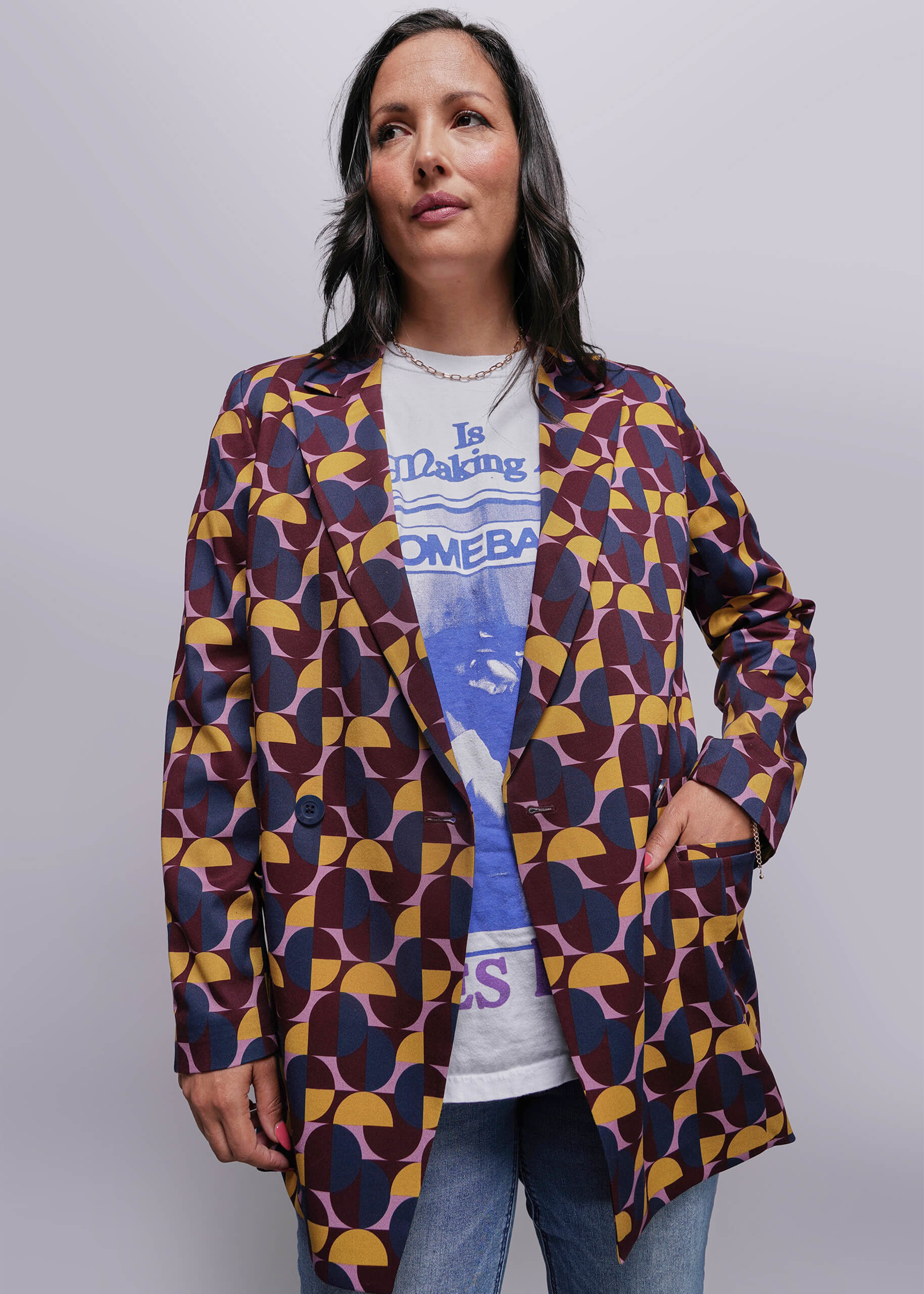 S=Woman wearing a patterned jacket over a graphic t-shirt on a plain background