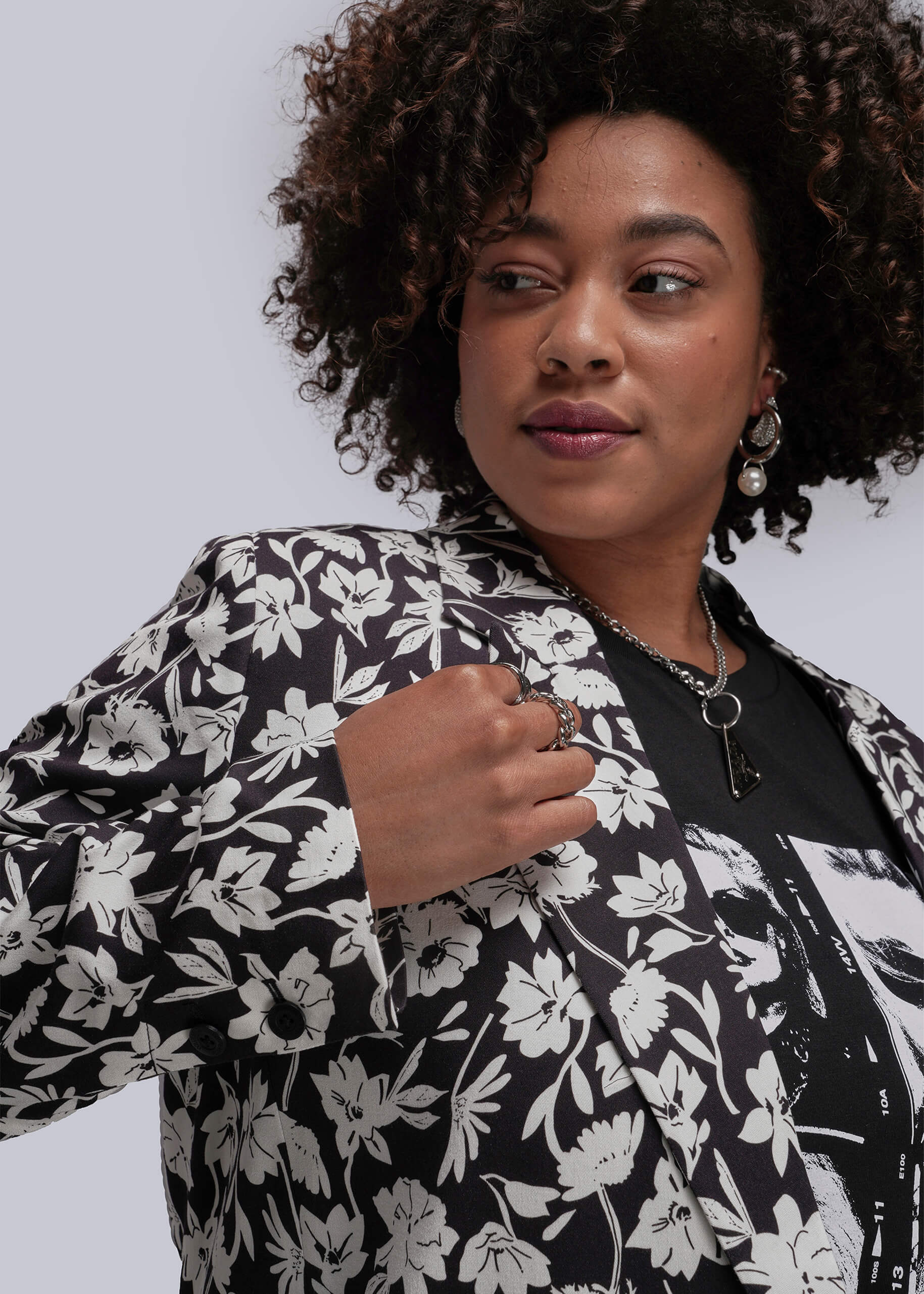 1X=Person wearing a black floral blazer against a plain background