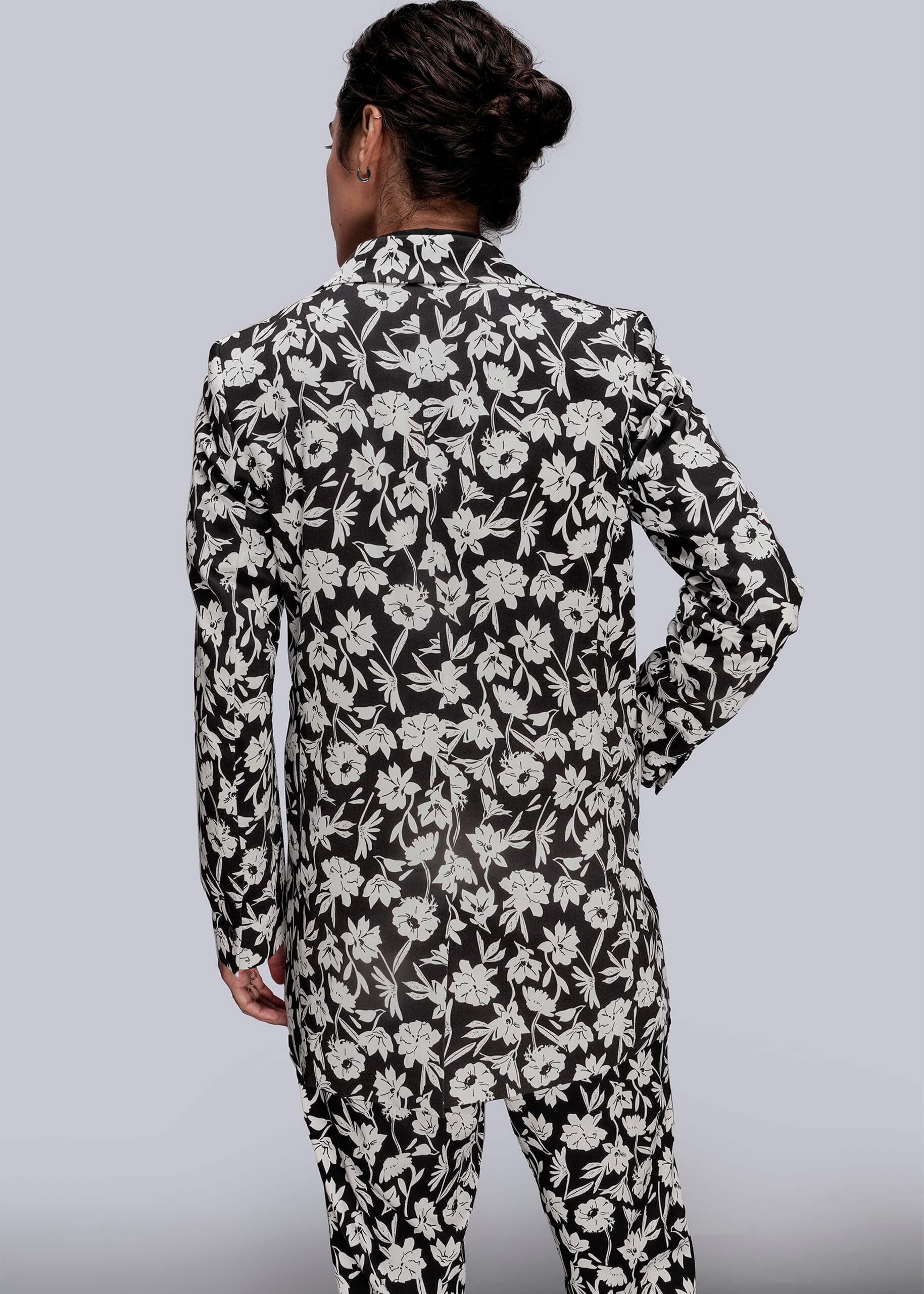 S=Person wearing a black and white floral suit on a gray background