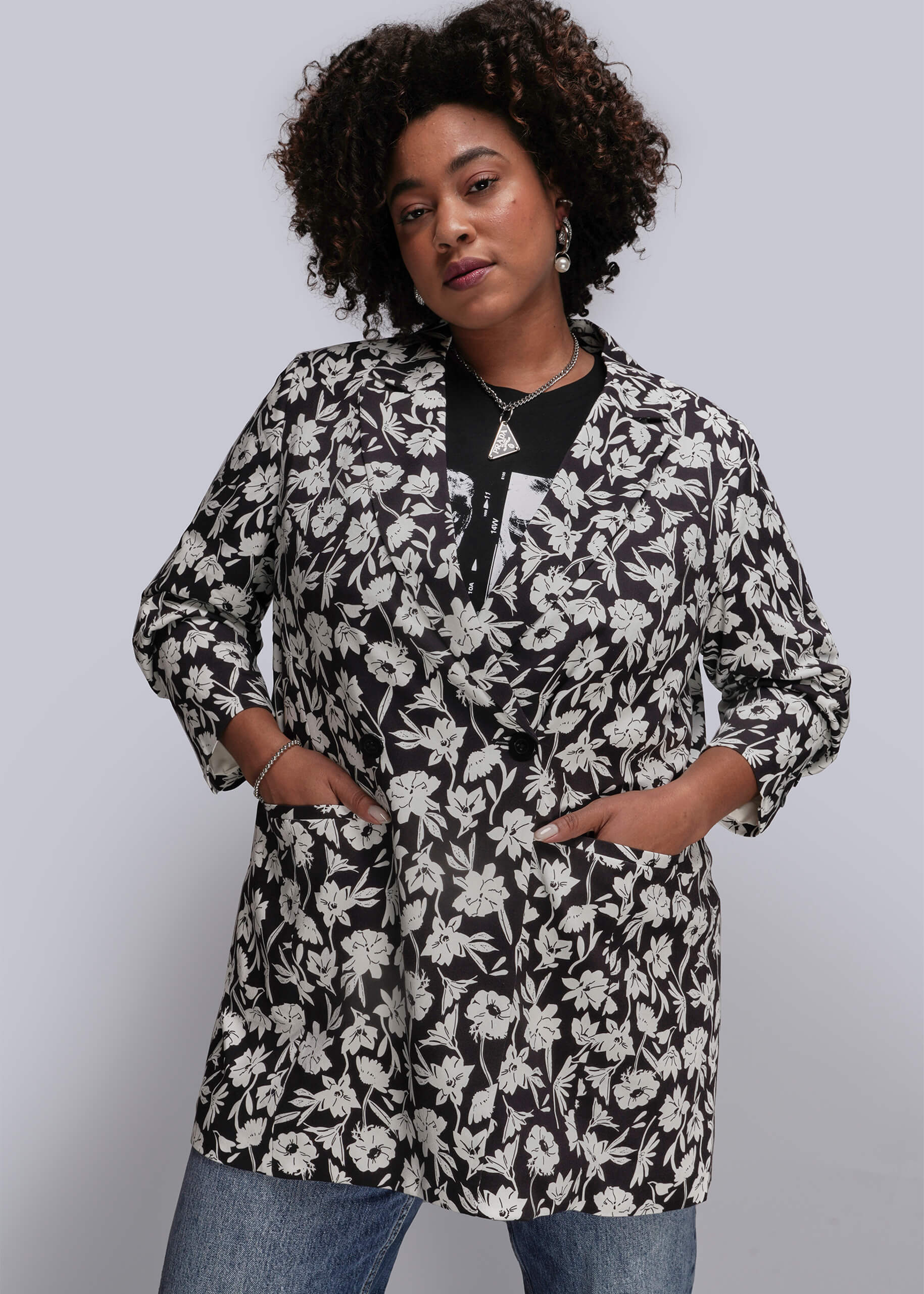 1X=Person wearing a black and white floral blazer against a plain background