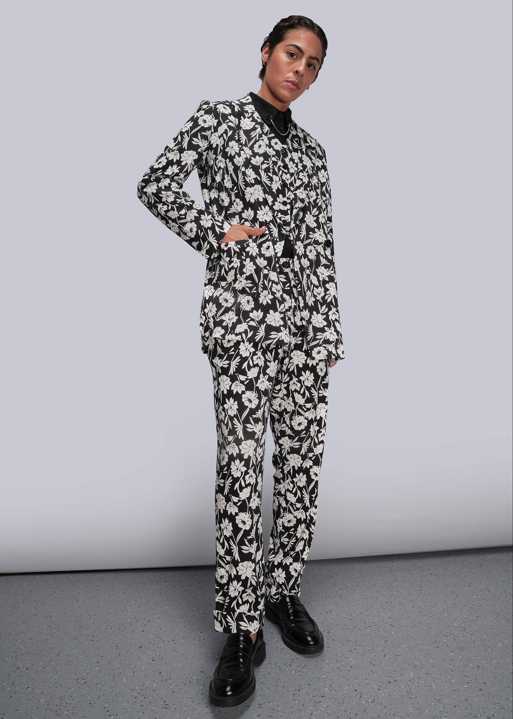 Person wearing a black and white floral suit against a plain background