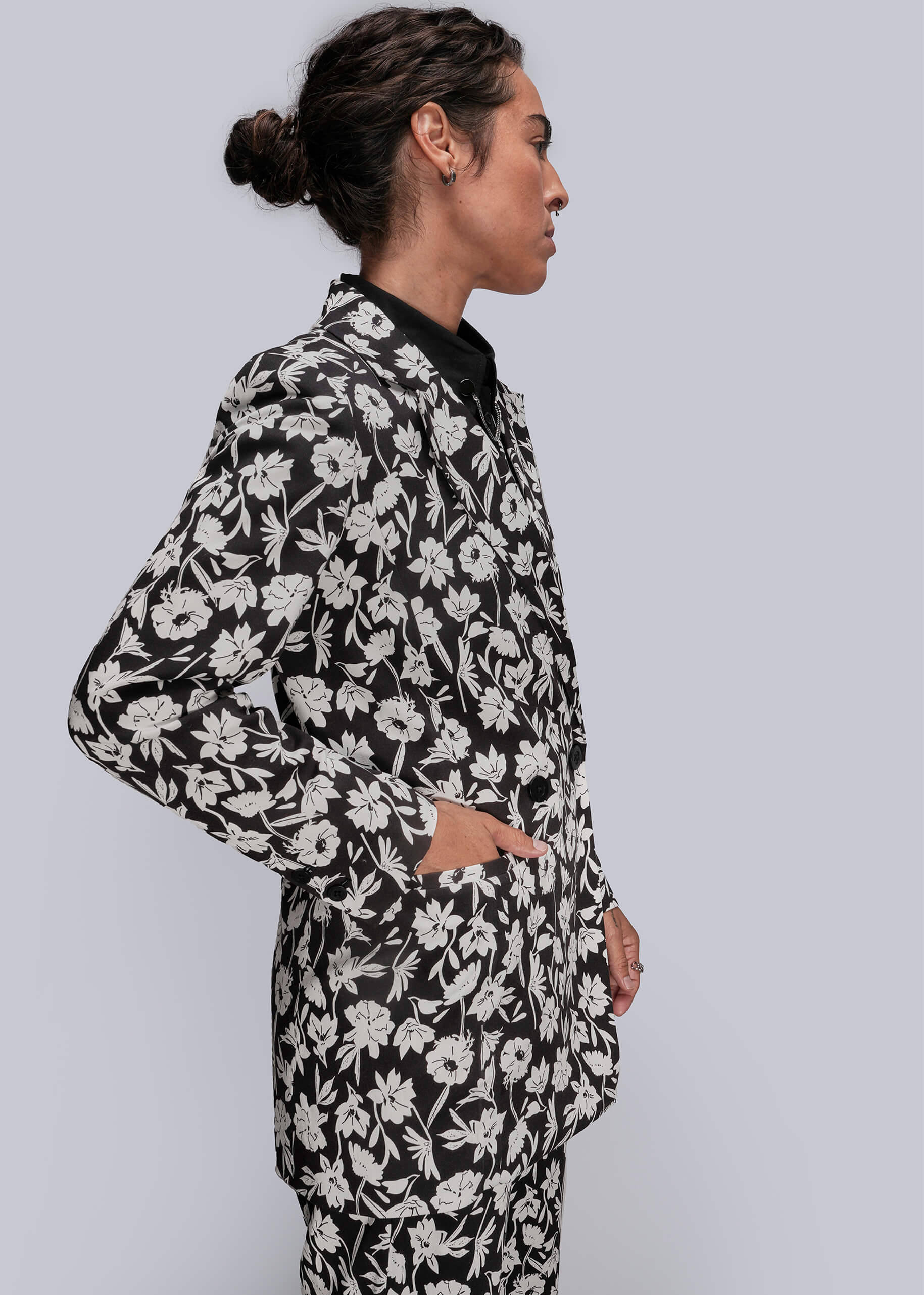 S=Person wearing a black floral patterned suit on a light gray background