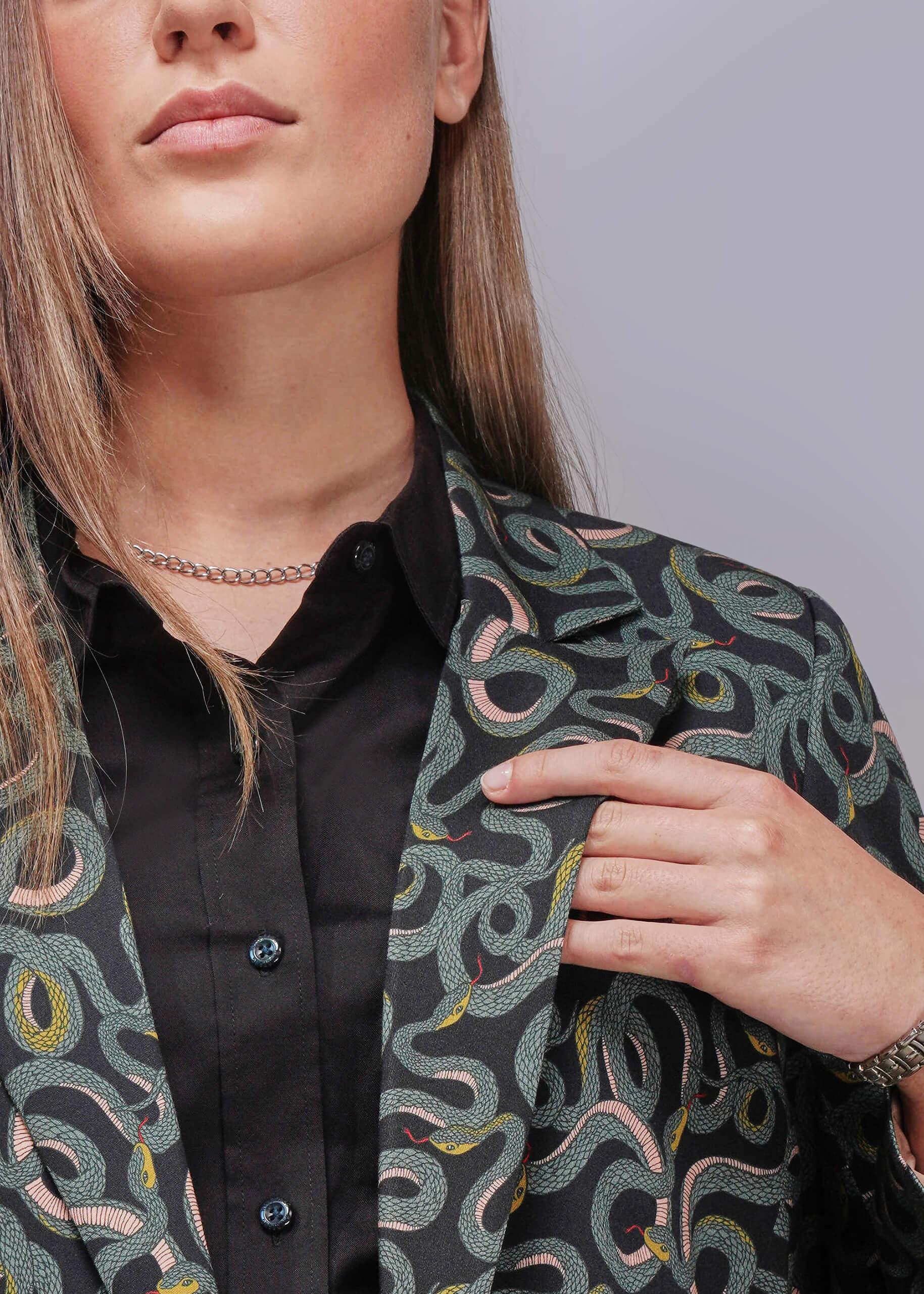 S=Person wearing a patterned jacket over a black shirt on a light gray background