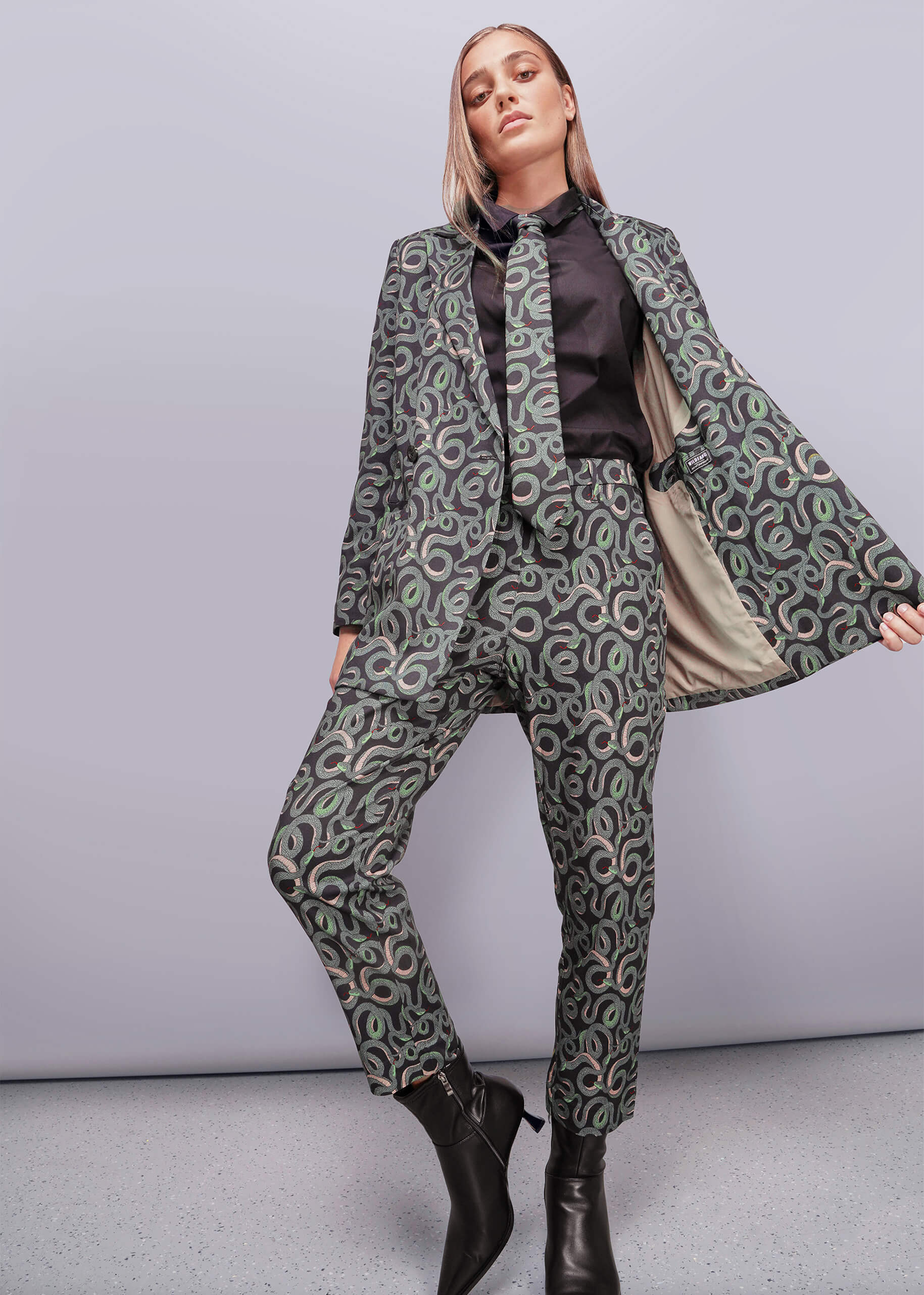 S=Woman wearing a patterned suit with a cape on a plain background