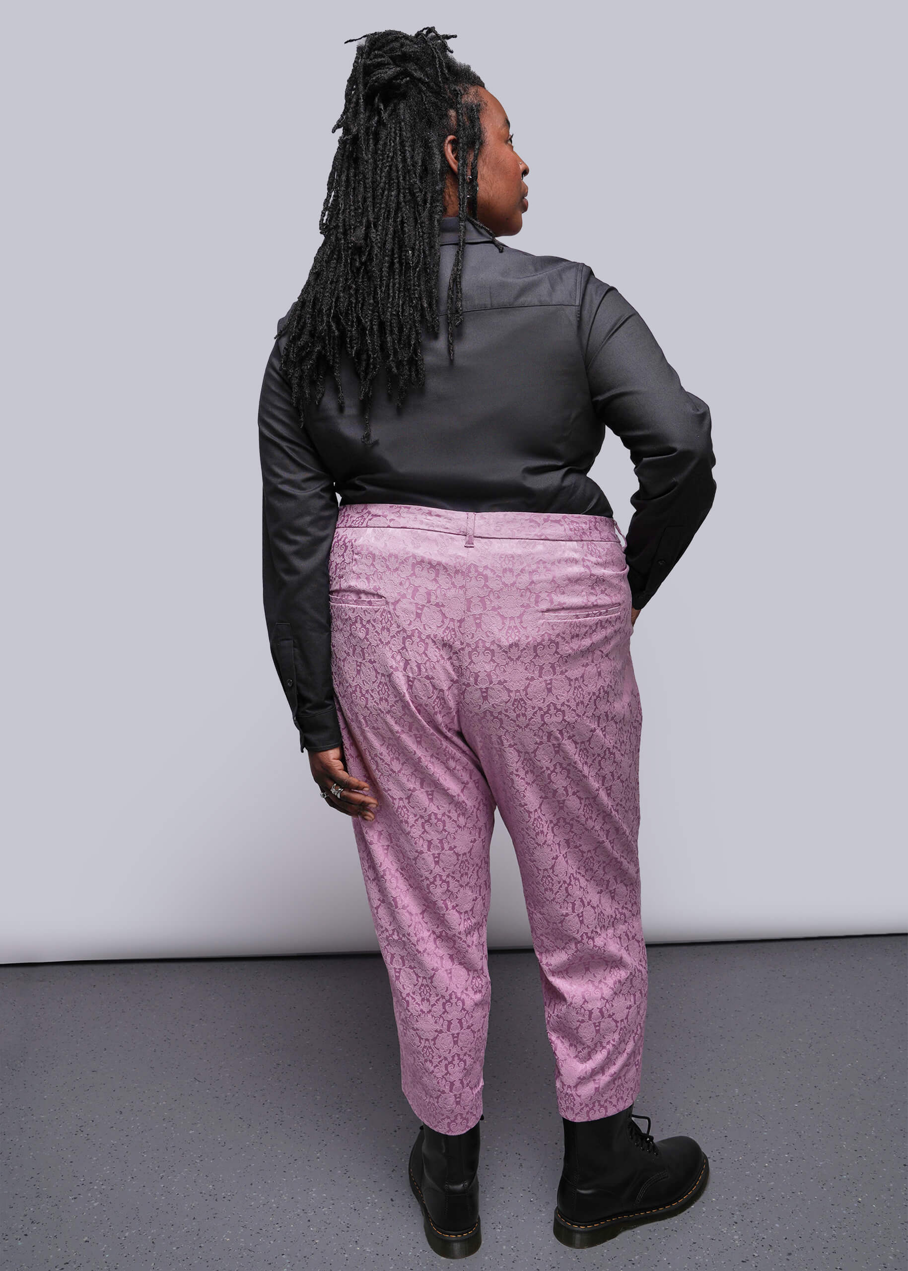 1X=Person wearing a black jacket and pink pants against a white background
