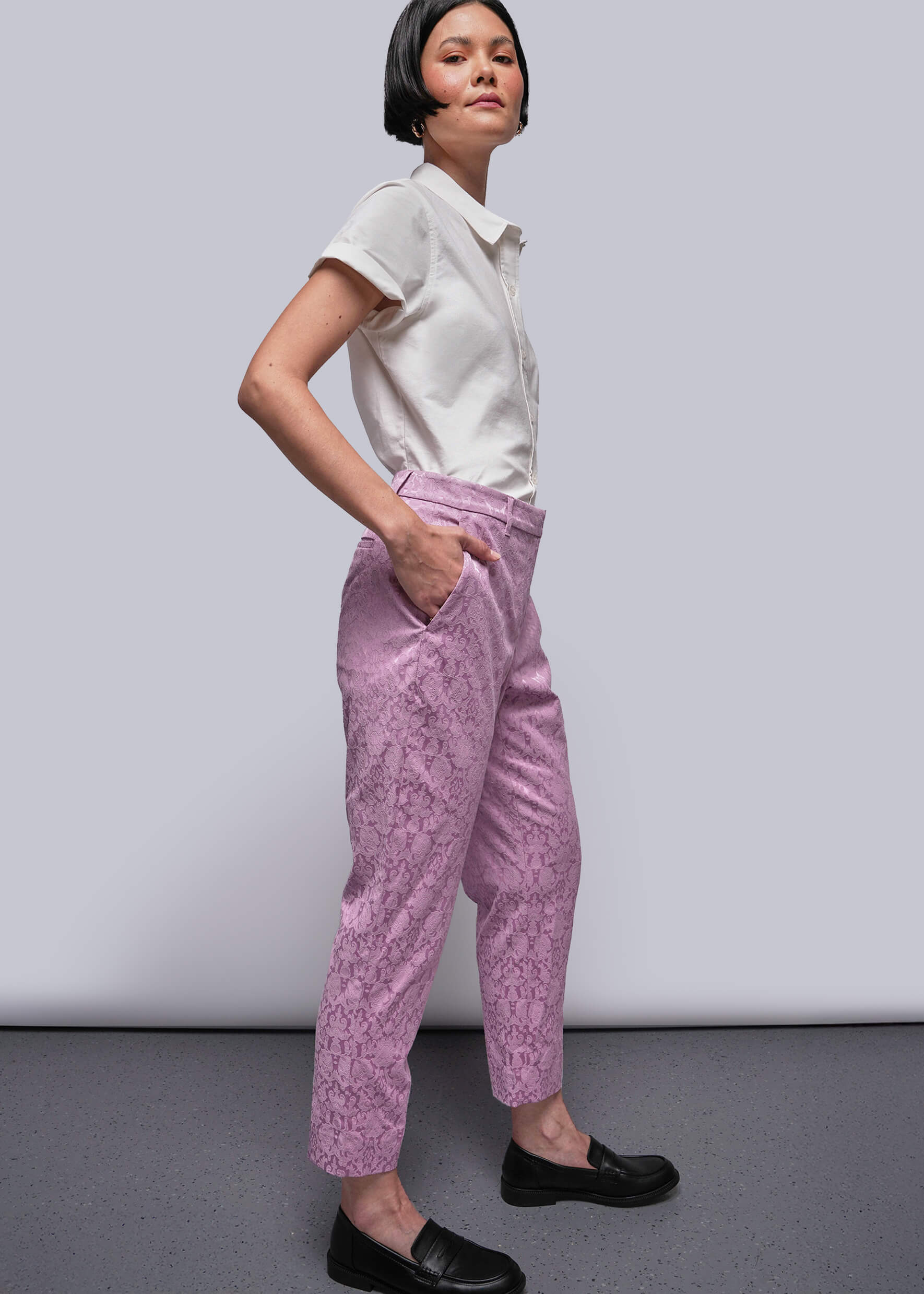S=Person wearing a white shirt and pink patterned pants against a plain background