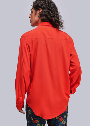 S=Person wearing a bright red shirt with colorful pants on a plain background