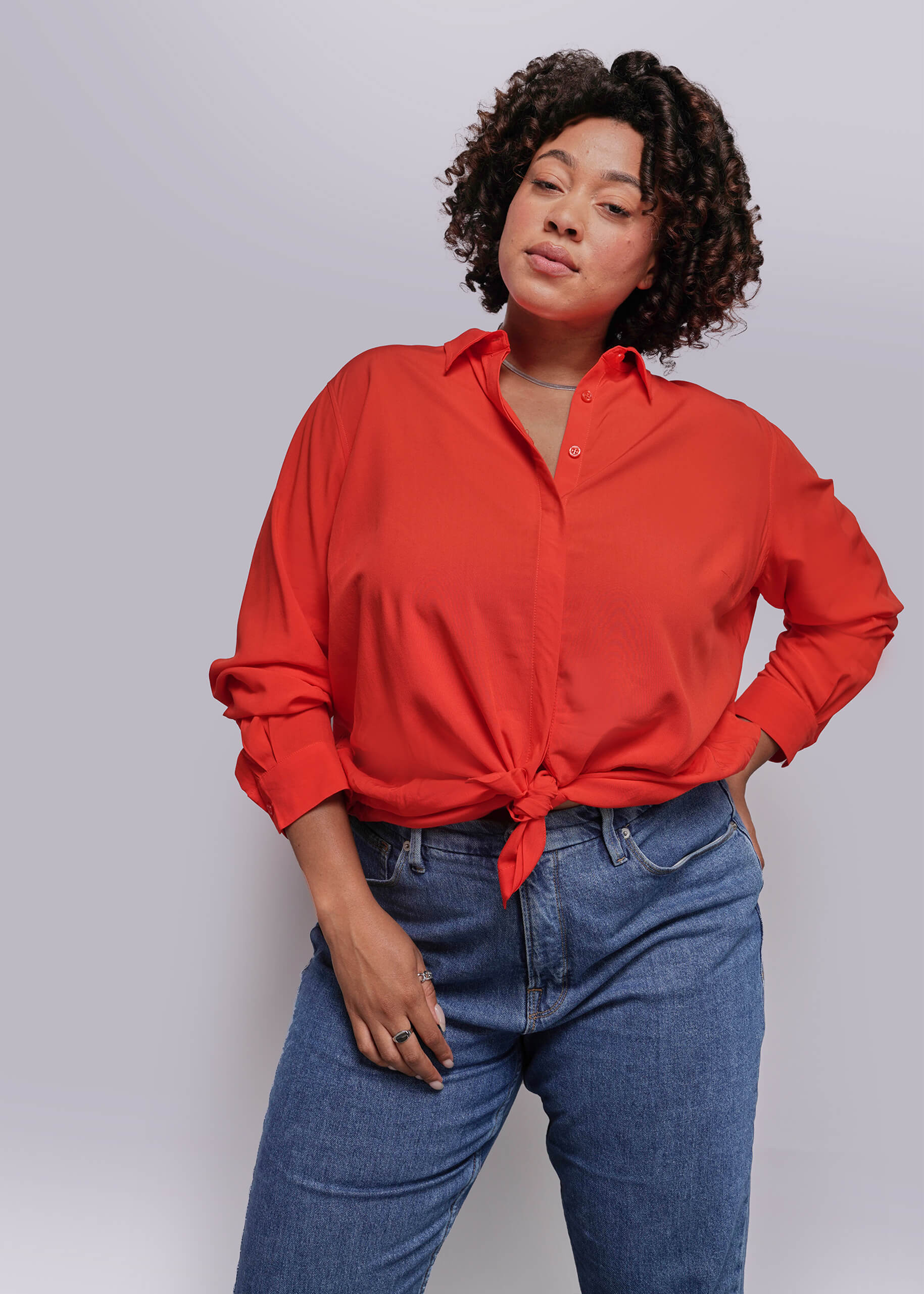 1X=Person wearing a red shirt and blue jeans against a plain background