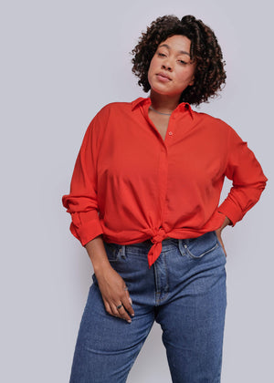 1X=Person wearing a red shirt and blue jeans against a plain background