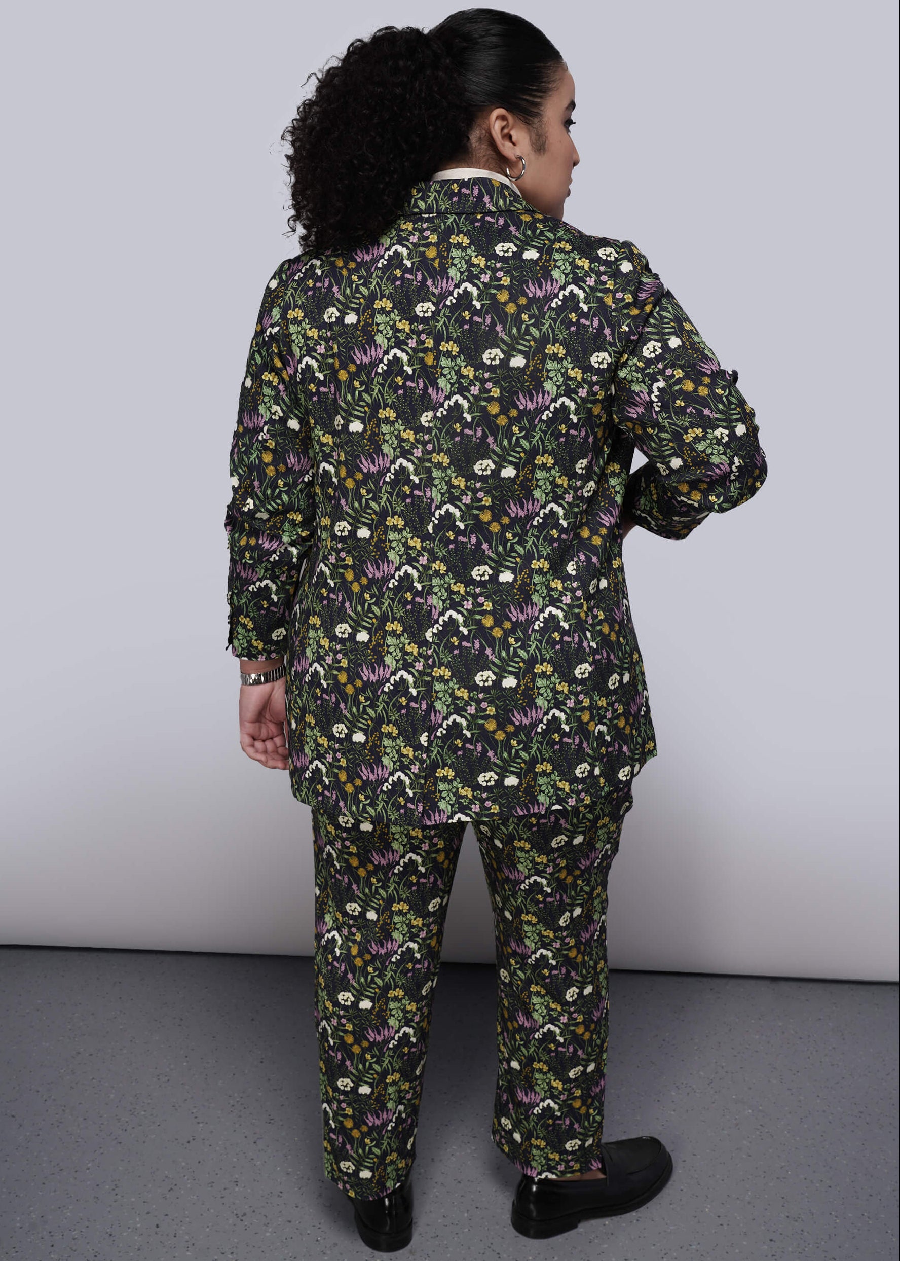 1X=Person wearing a floral patterned suit against a plain background