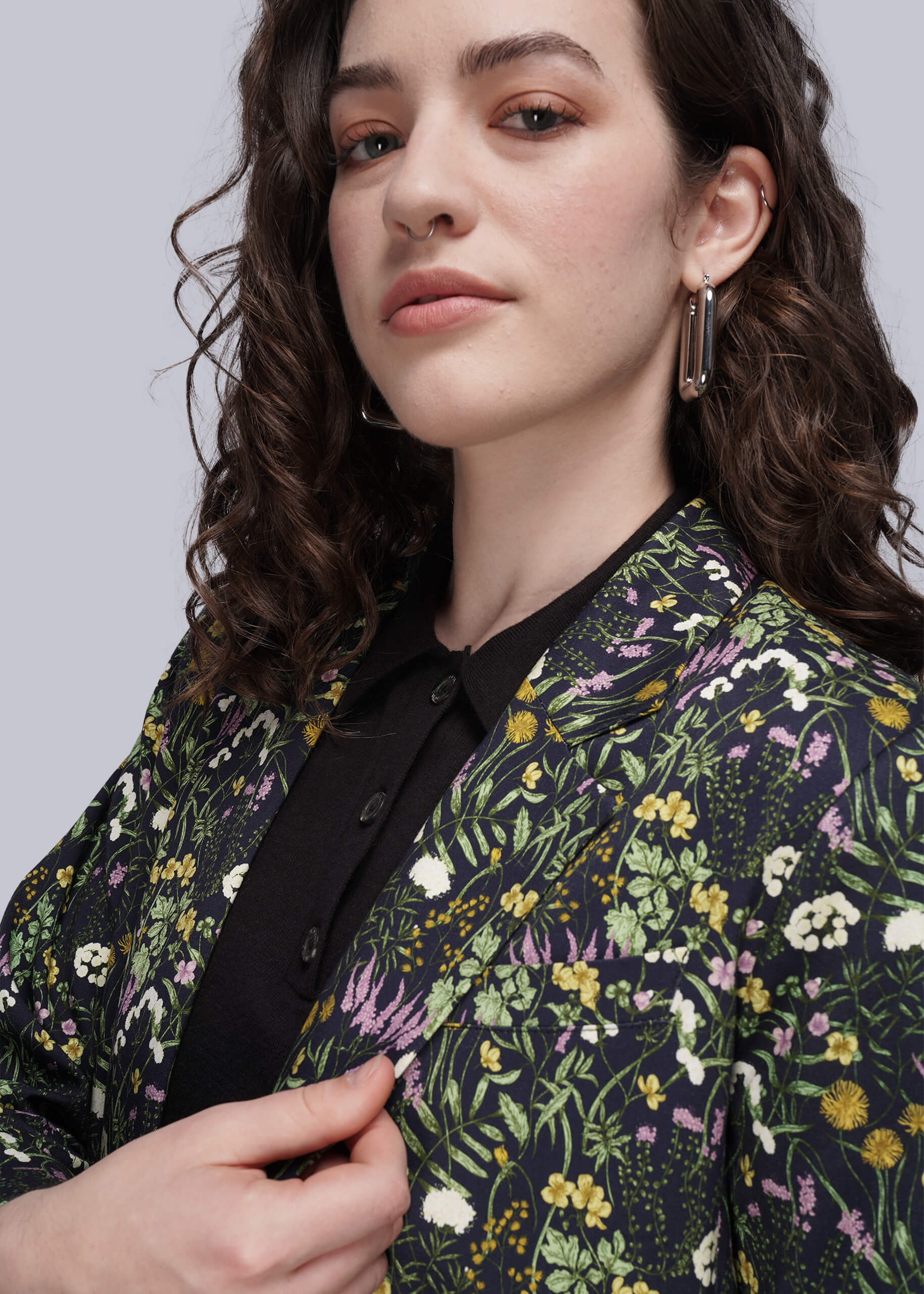 S=Woman wearing a floral patterned jacket against a plain background
