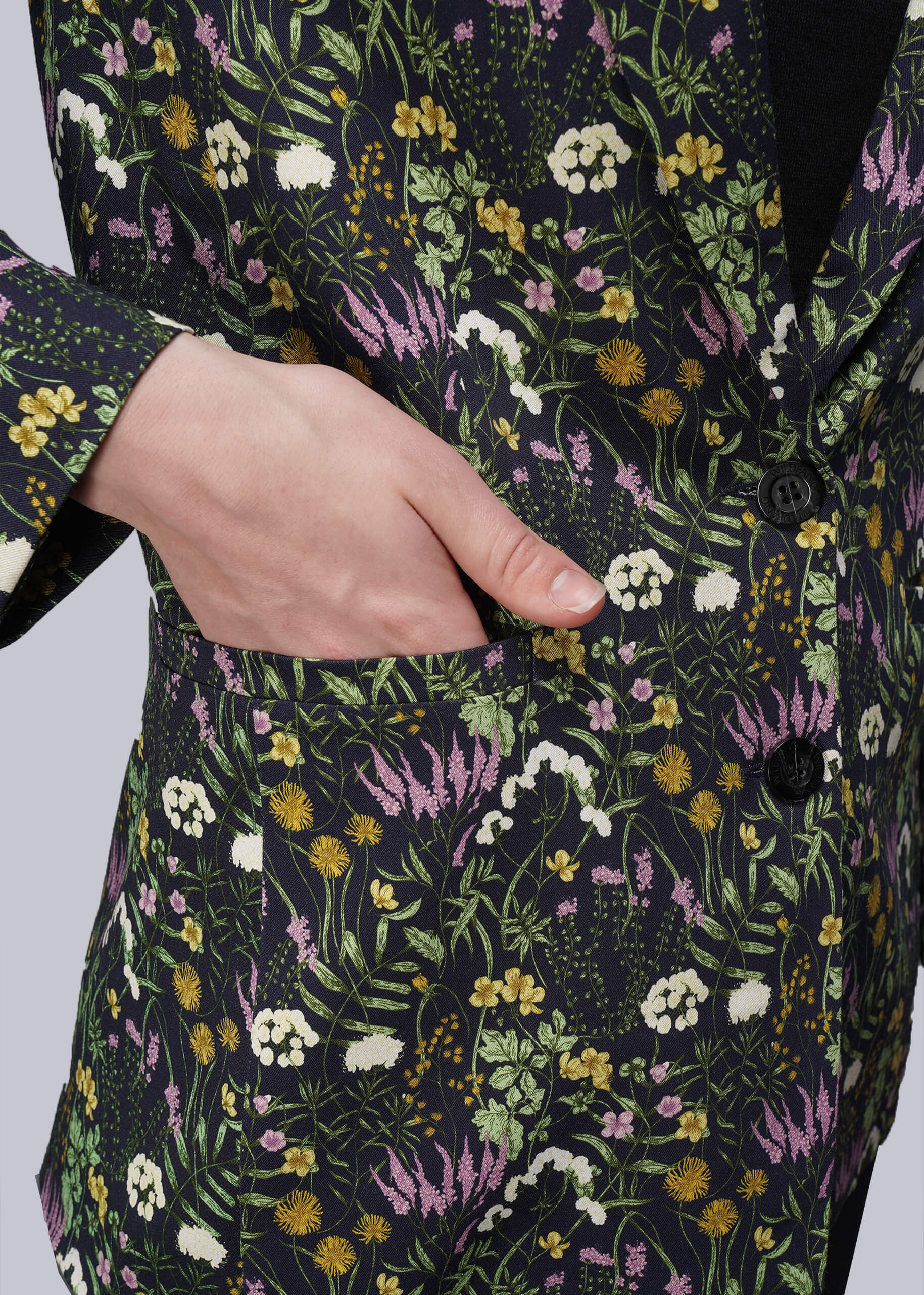 S=Floral patterned garment with a hand in the pocket on a plain background