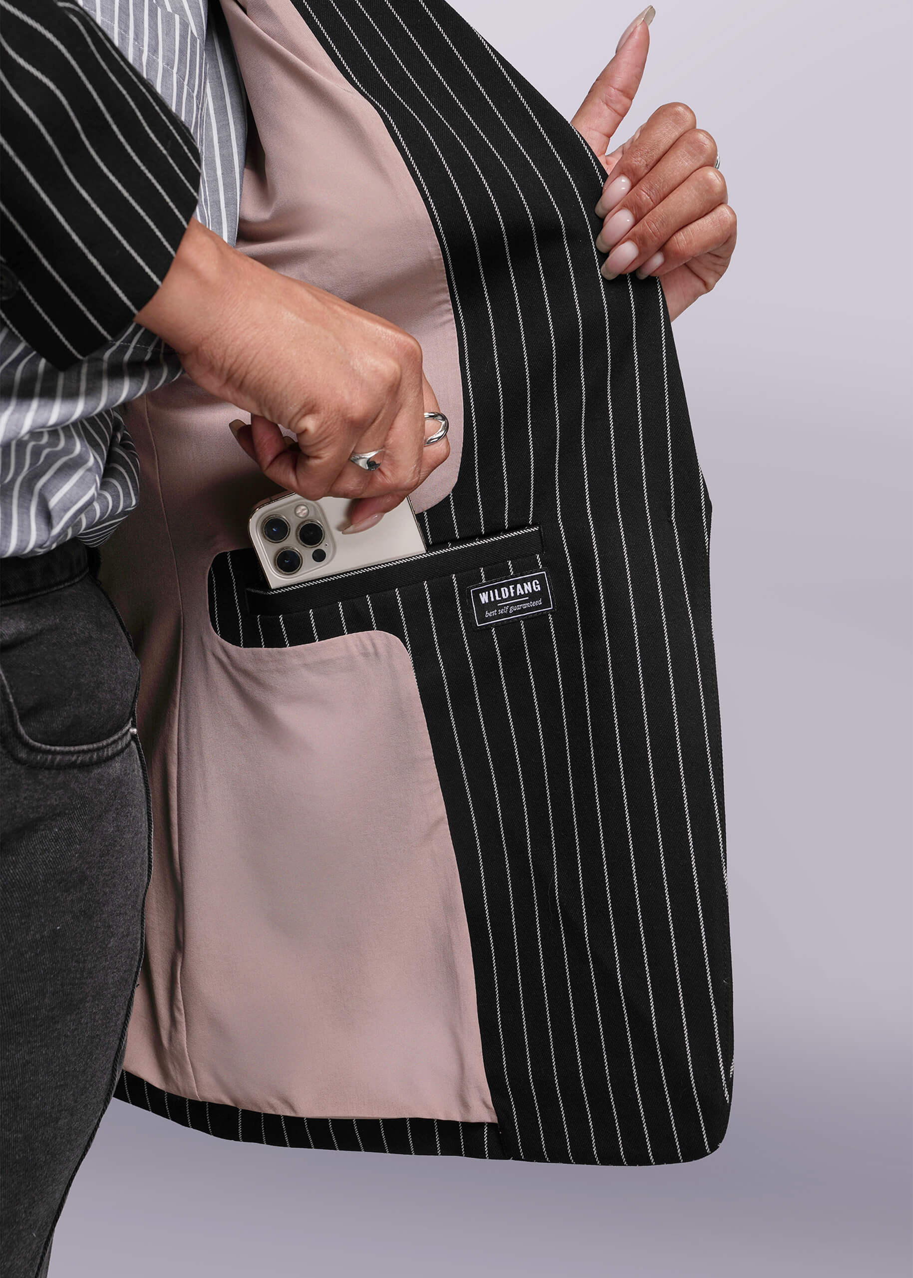 1X=Person holding a black pinstripe blazer open with a visible brand label on a light gray background