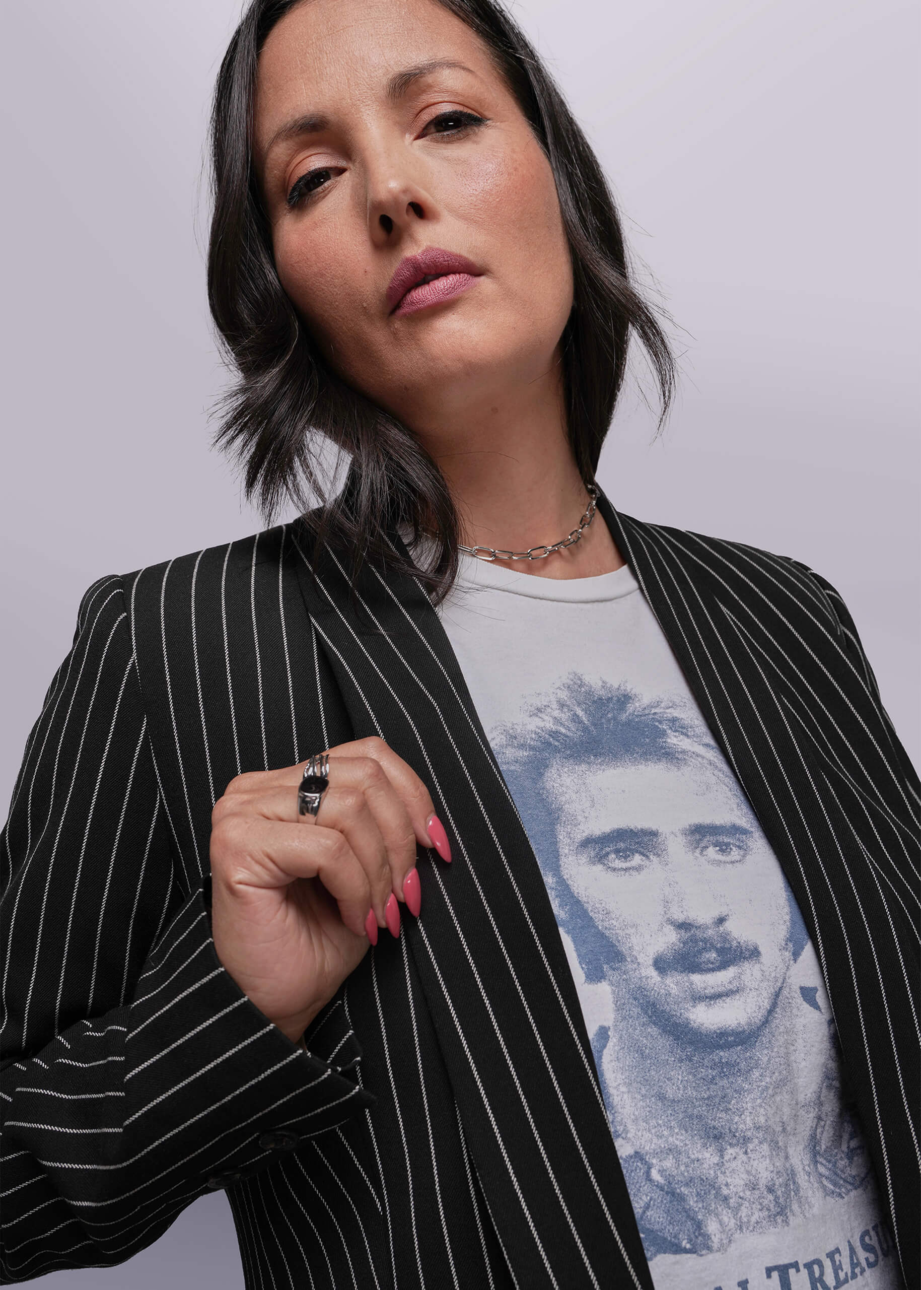 S=Woman wearing a black pinstripe blazer over a graphic t-shirt with a plain background