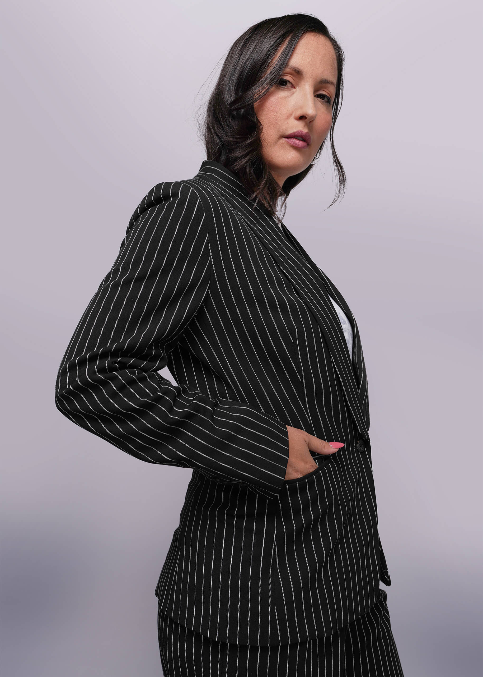 S=Woman wearing a black pinstripe suit against a gray background