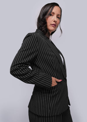 S=Woman wearing a black pinstripe suit against a gray background