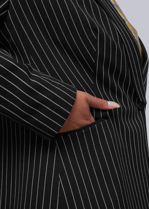 1X=Close-up of a black pinstripe suit with a hand adjusting the jacket
