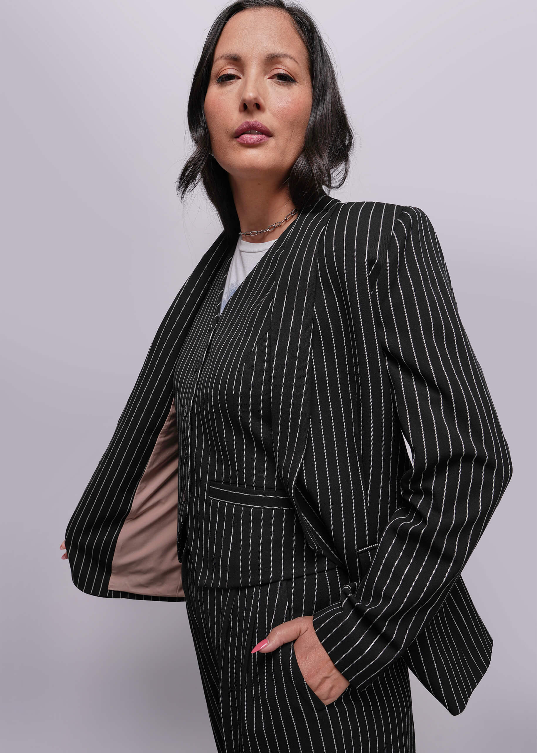 S=Woman wearing a black pinstripe suit against a plain background