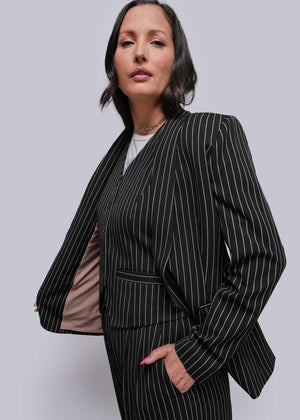 S=Woman wearing a black pinstripe suit against a plain background