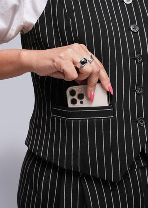 1X=Person wearing a black pinstripe suit with a phone in the pocket against a neutral background