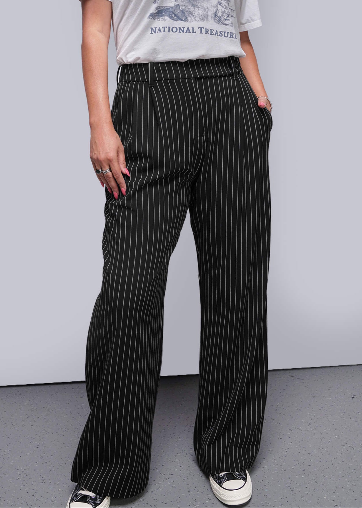 Person wearing a graphic t-shirt and pinstripe pants against a plain background