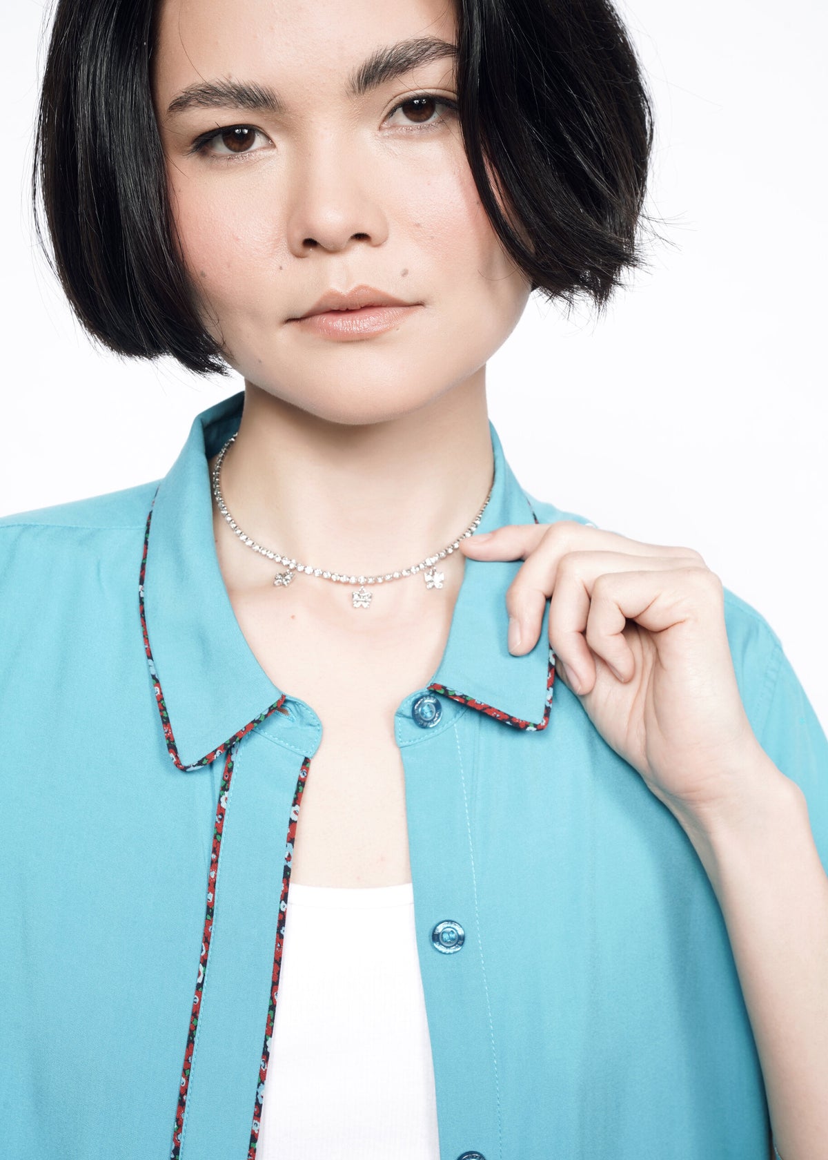 Close-up of Model wearing the Empower Button Up in Coastal with Floral print piped trim in size XS, with a white T and necklace