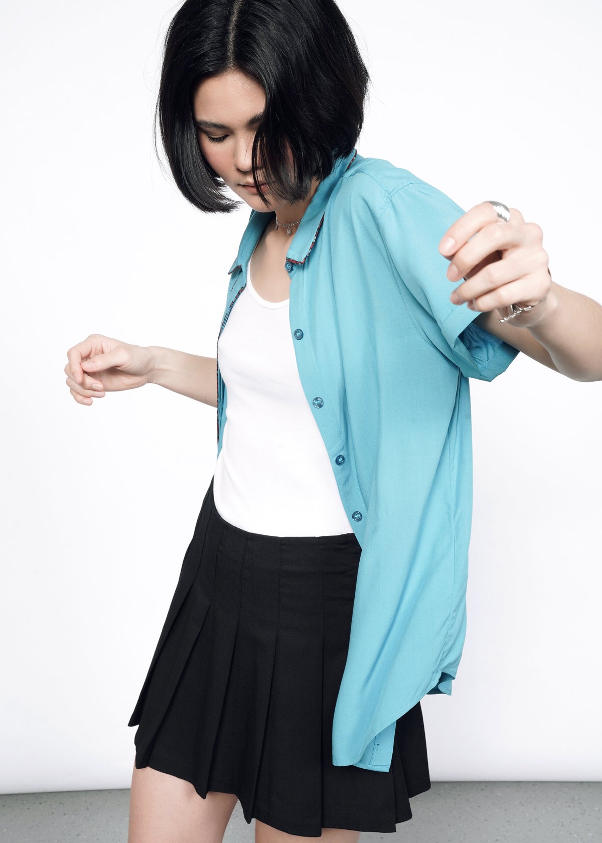 Model wearing the Empower Button Up in Coastal with Floral print piped trim in size XS, with a white T, black skirt