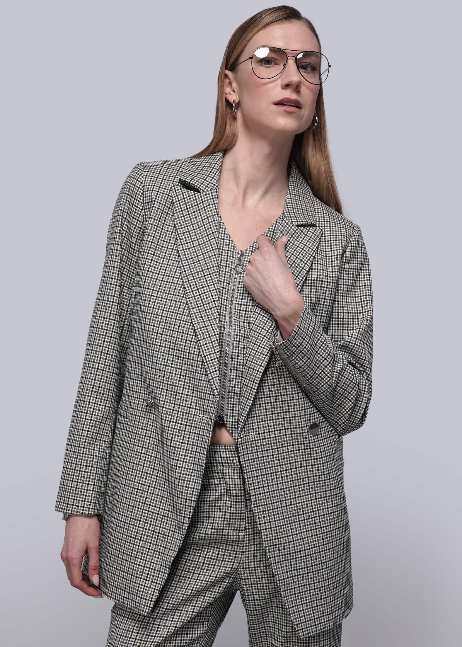 Person wearing matching plaid vest, blazer, and trouser against plain background.