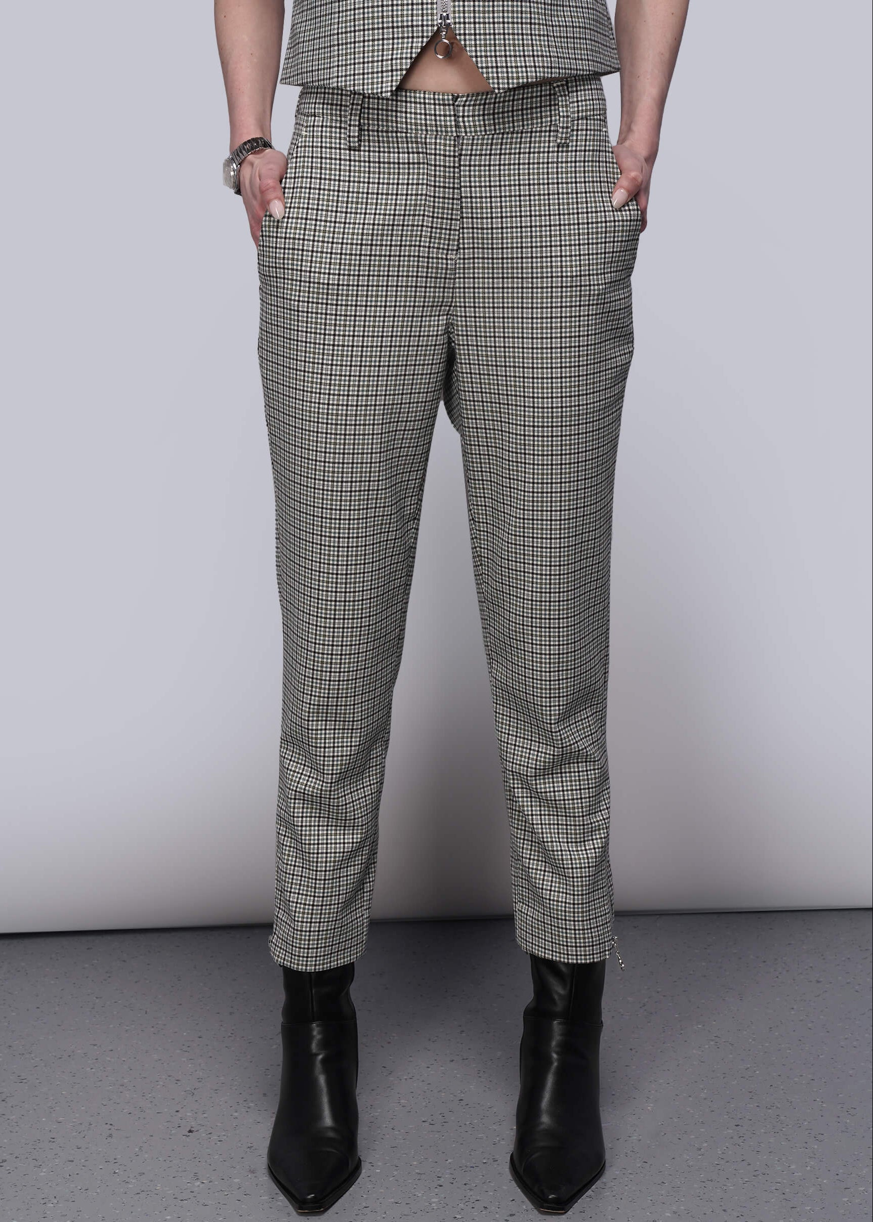 Person wearing plaid pants and black boots on a plain background