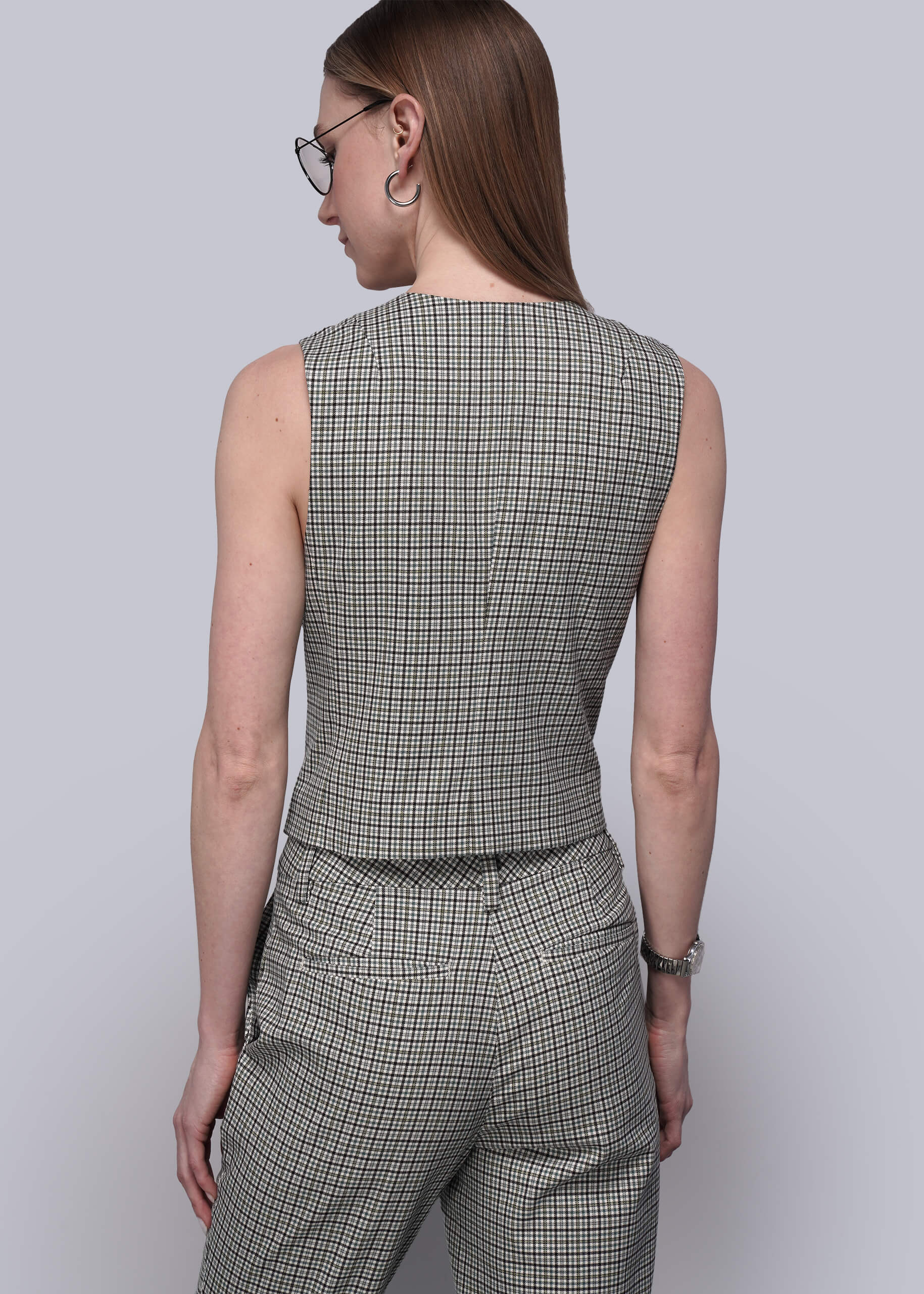 S=Back of person wearing a plaid vest and pants on a light gray background