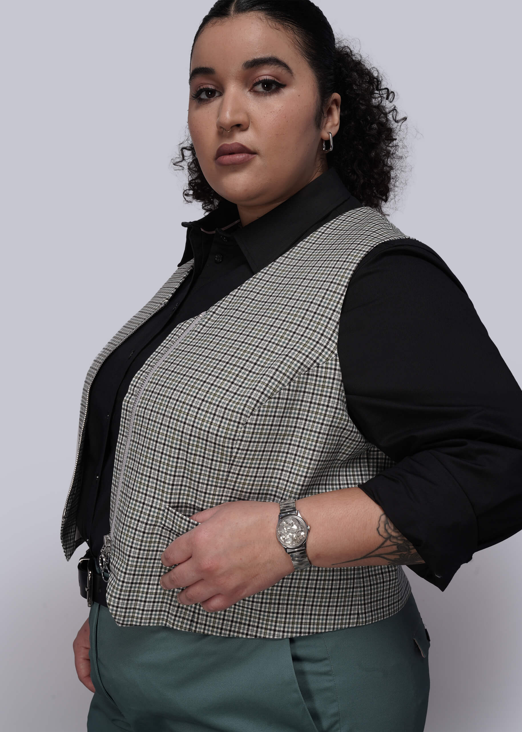 1X=Person wearing a checkered vest over a black shirt on a white background