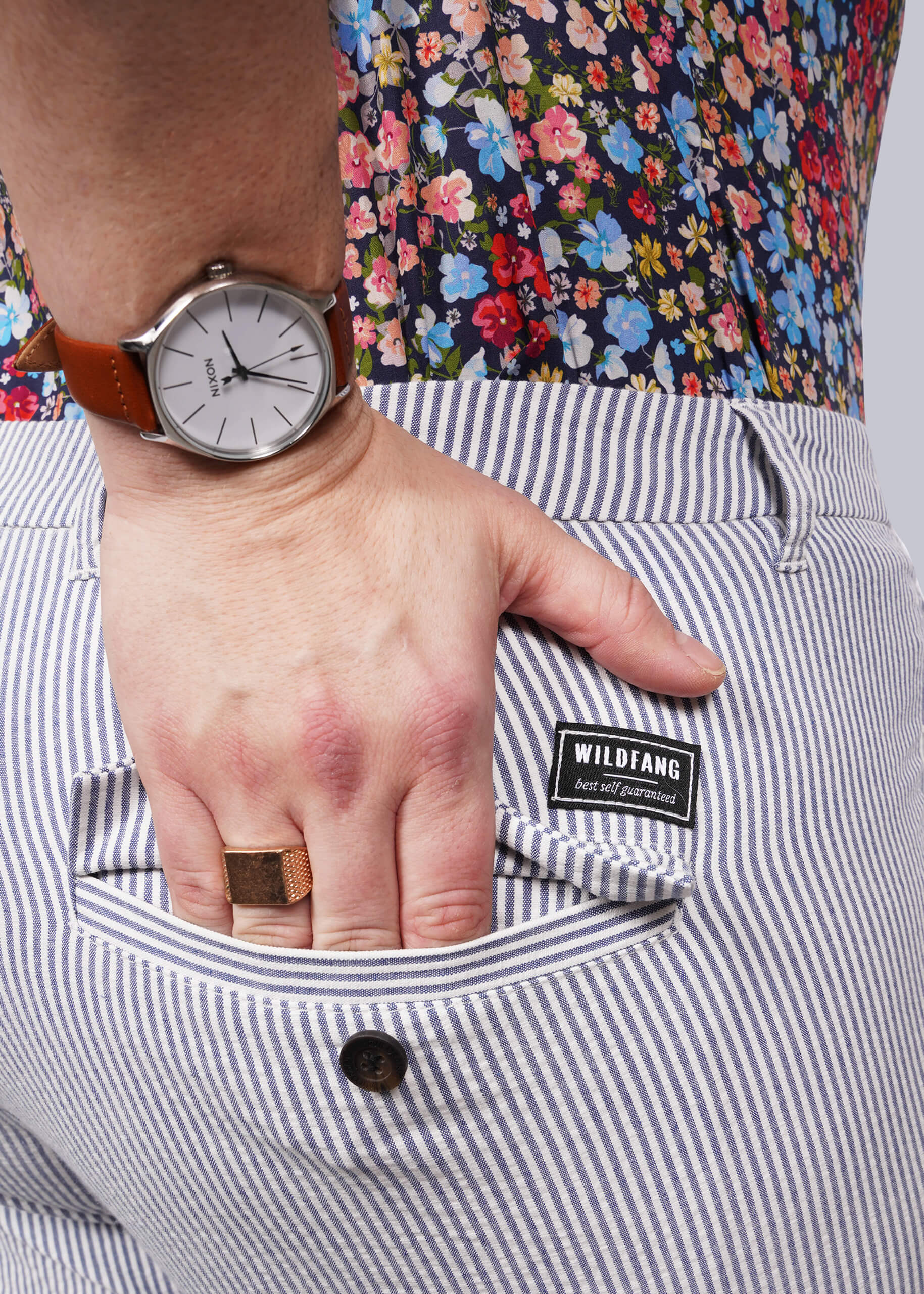 1X=Hand with a watch on a striped pant pocket, featuring the brand 'WILDFANG'.