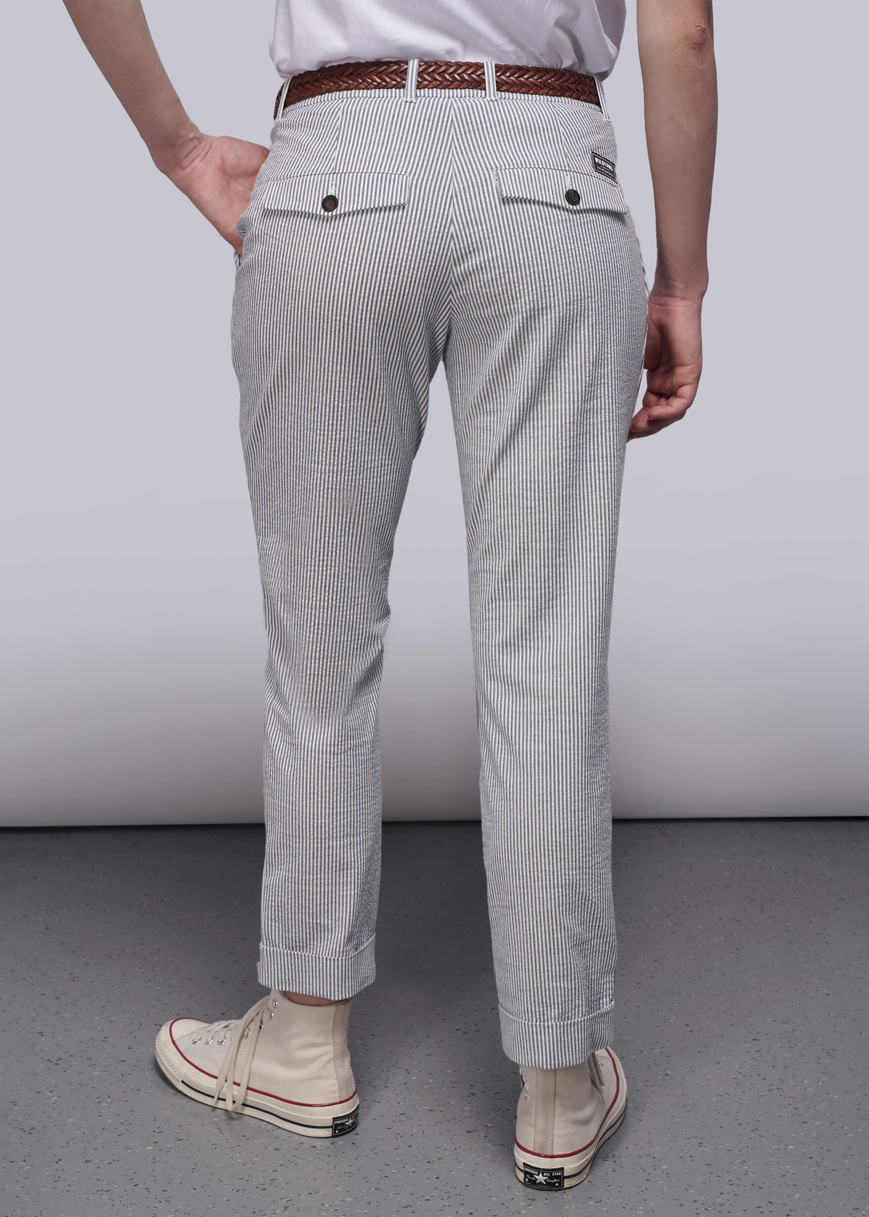 S=Person wearing light blue striped pants with a white shirt and beige sneakers on a plain background