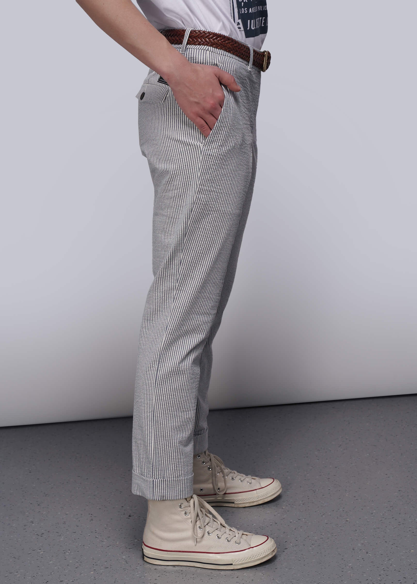 S=Person wearing light blue seersucker pants and white sneakers on a plain background