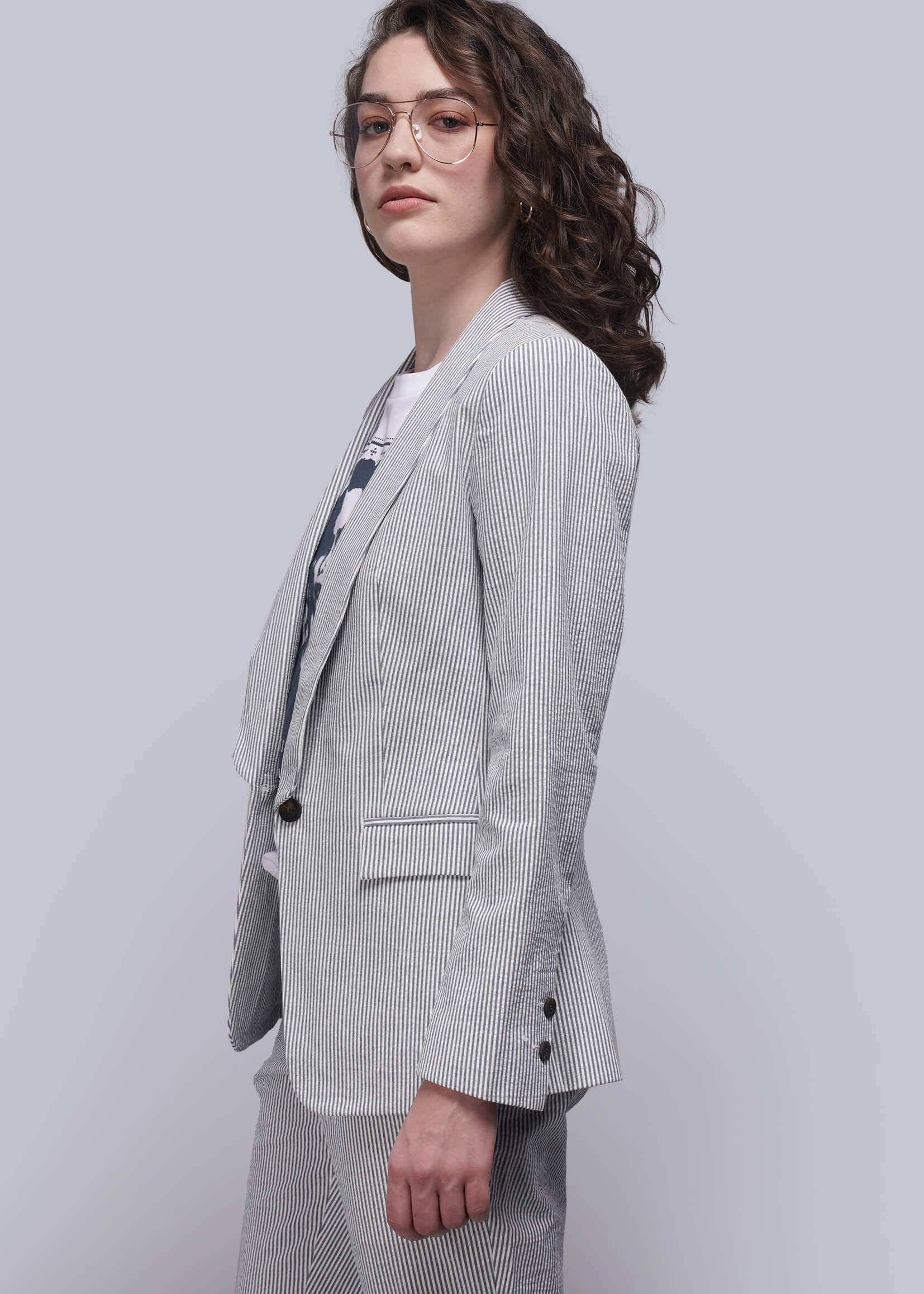 S=Person wearing a light blue striped seersucker suit on a plain background